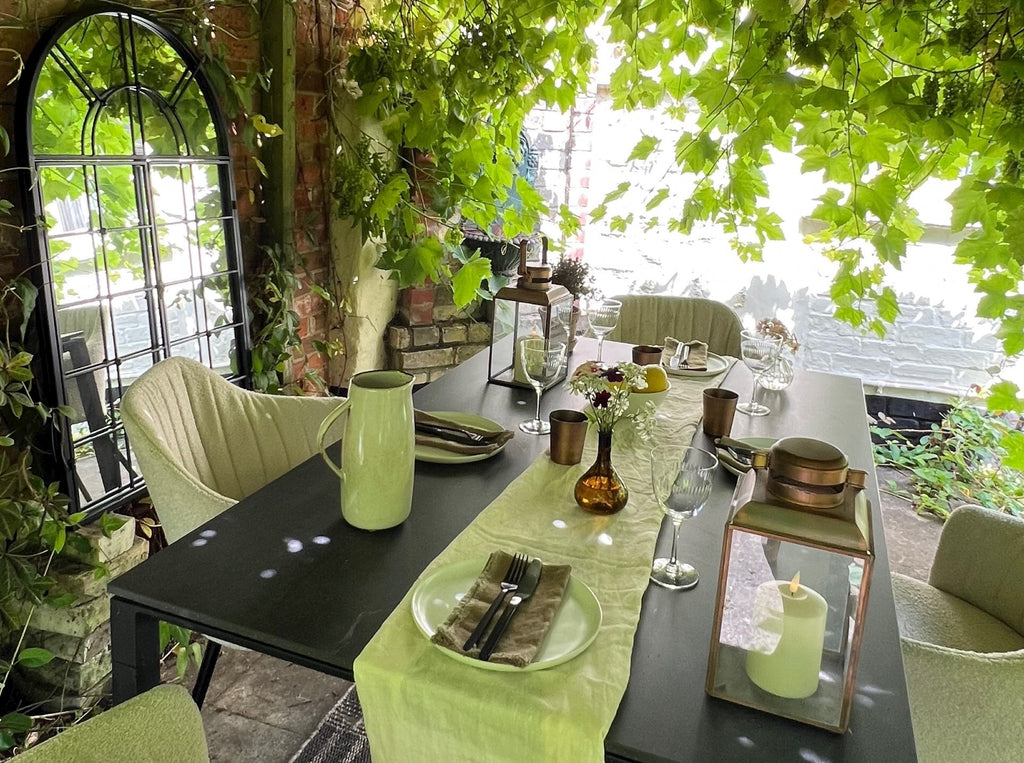 green lush pergola with modern dining setting with sand boucle outdoor dining chairs and ceramic black outdoor table 
