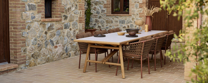 Ein Holztisch mit stilvollen Rattanstühlen, geschmückt mit einer dekorativen Schüssel und einer minimalistischen Tischgestaltung.