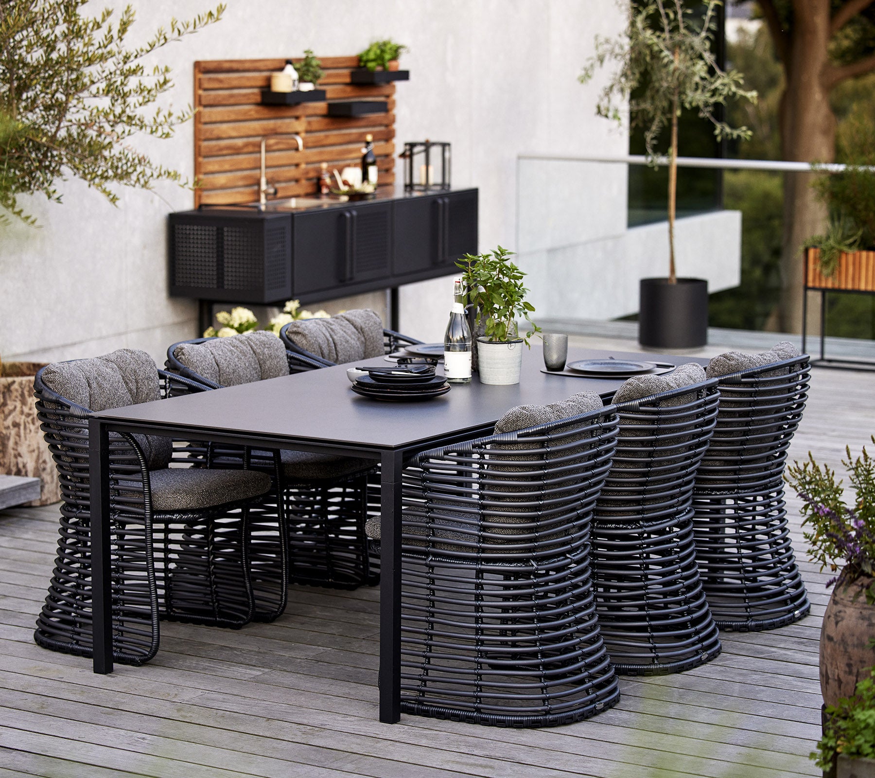 Ein modernes Esszimmer-Set mit einem rechteckigen Tisch und sechs stilvollen Korbstühlen, ergänzt durch dekorative Elemente im Hintergrund.
