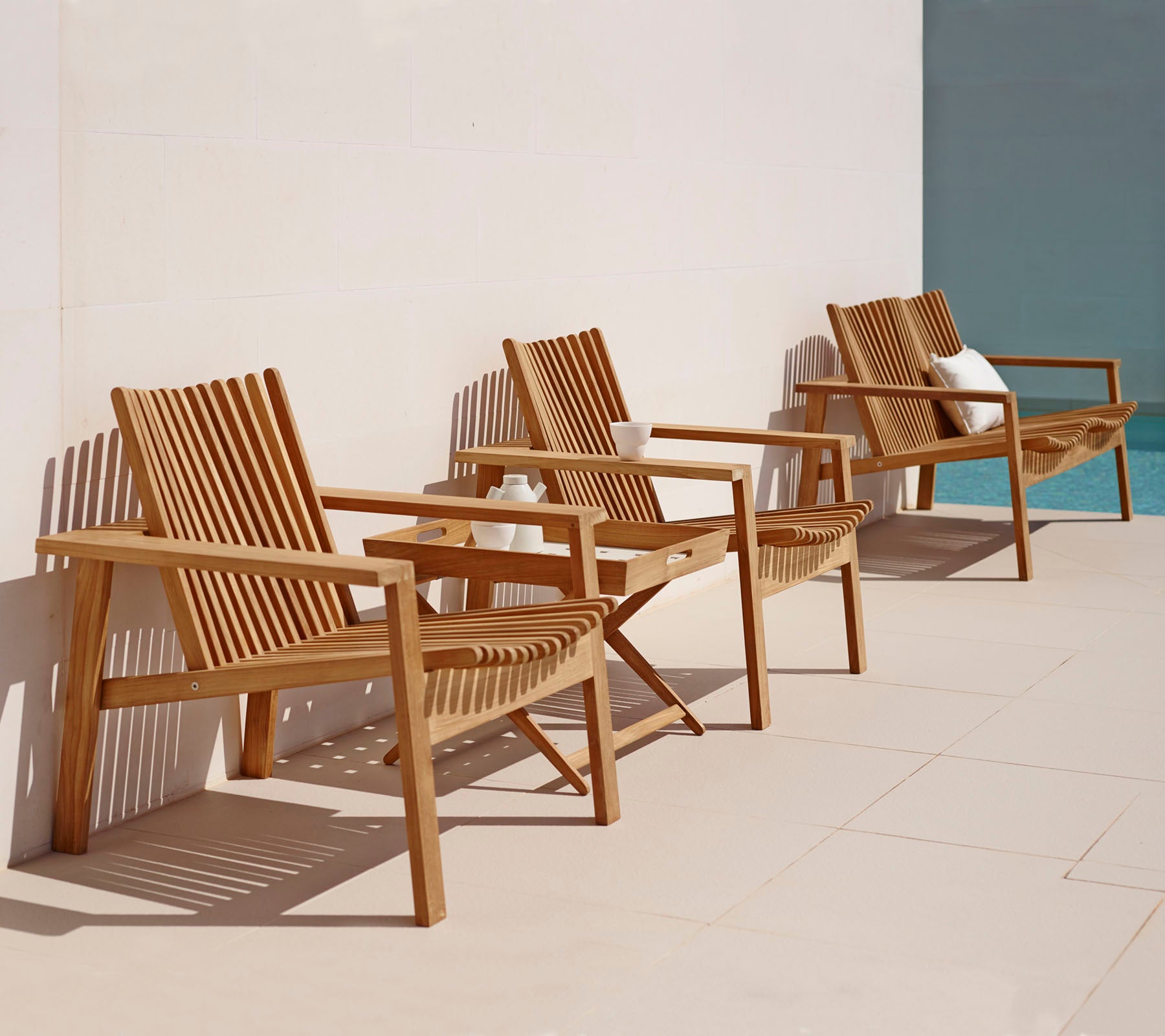 Drei Holzliegestühle mit schrägen Designs in einer Reihe, die einen einfachen, eleganten Stil für Entspannung bieten.