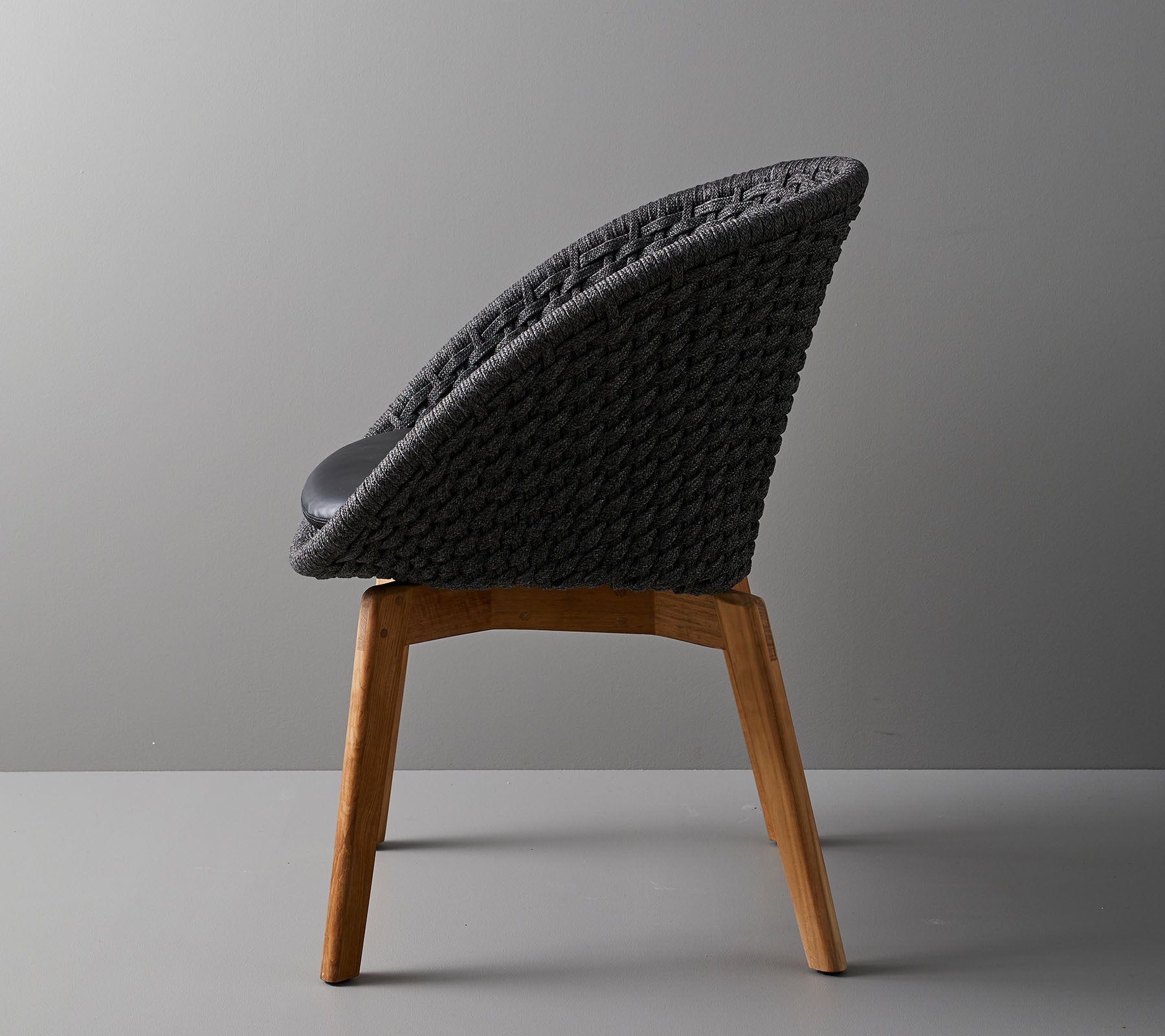 Stylischer Stuhl mit geflechtener Rückenlehne und Holzbeinen, der ein modernes Design bietet, das ideal für zeitgenössische Räume ist.