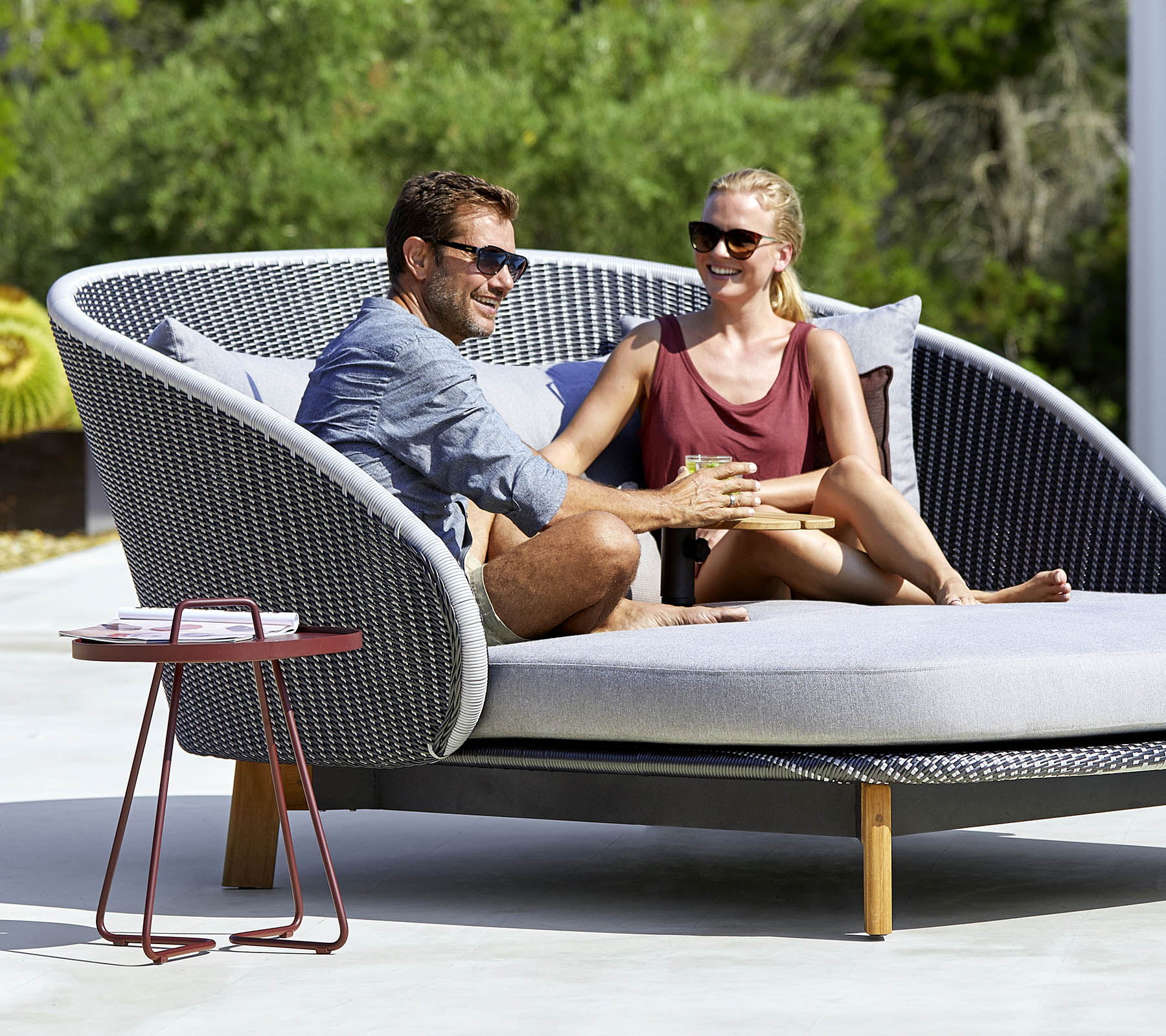 Ein Paar genießt einen gemütlichen Moment zusammen auf einem stilvollen, geschwungenen Outdoor-Sofa mit einem Beistelltisch in der Nähe.