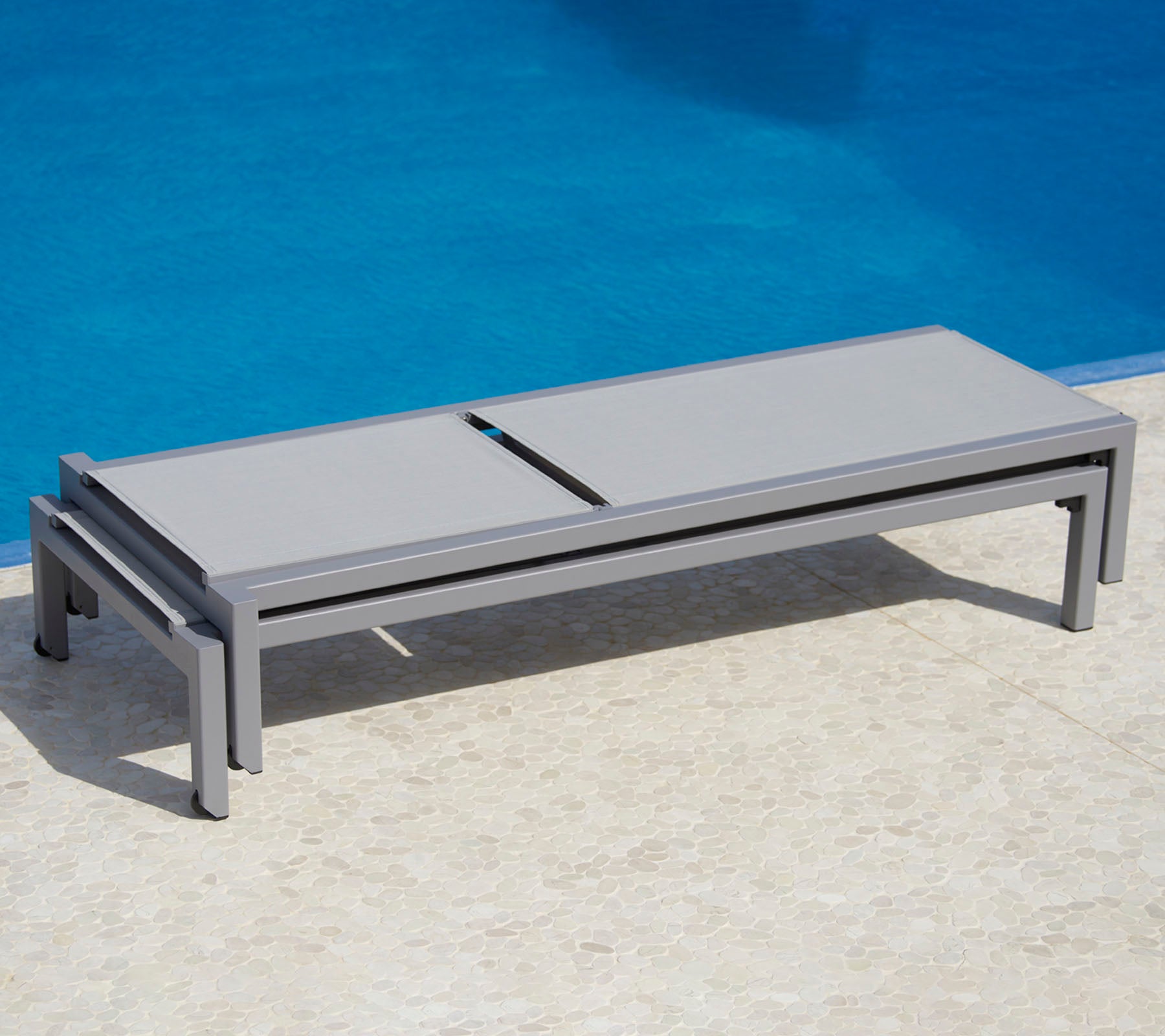 Stylisches graues Loungesofa neben einem Pool, das ein schlankes Design und praktische Funktionalität zur Entspannung bietet.