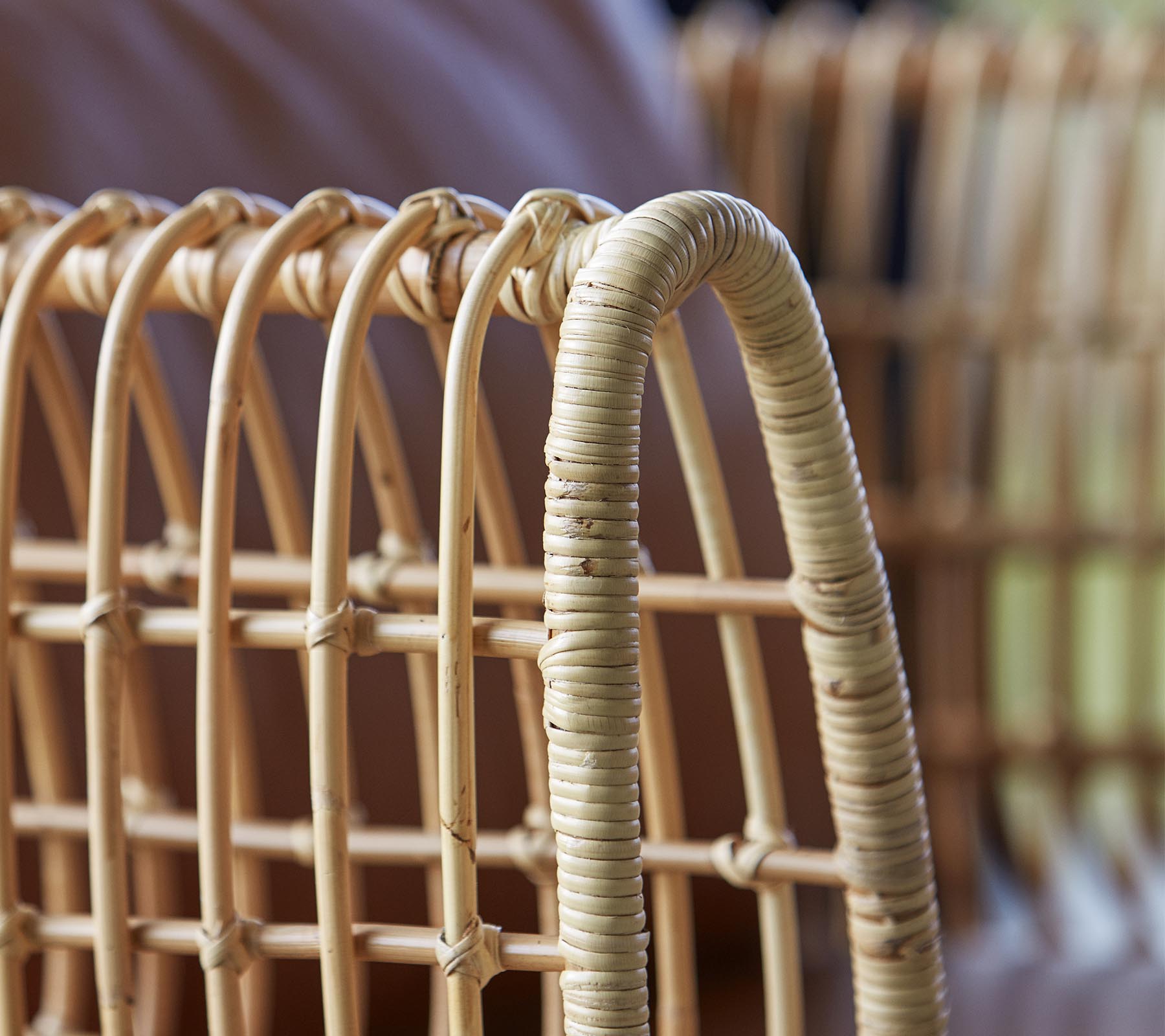 Nahaufnahme eines geflochtenen Rattanstuhls, der gekrümmte Linien und eine natürliche Oberfläche aufweist, die seine Handwerkskunst und sein Design hervorhebt.