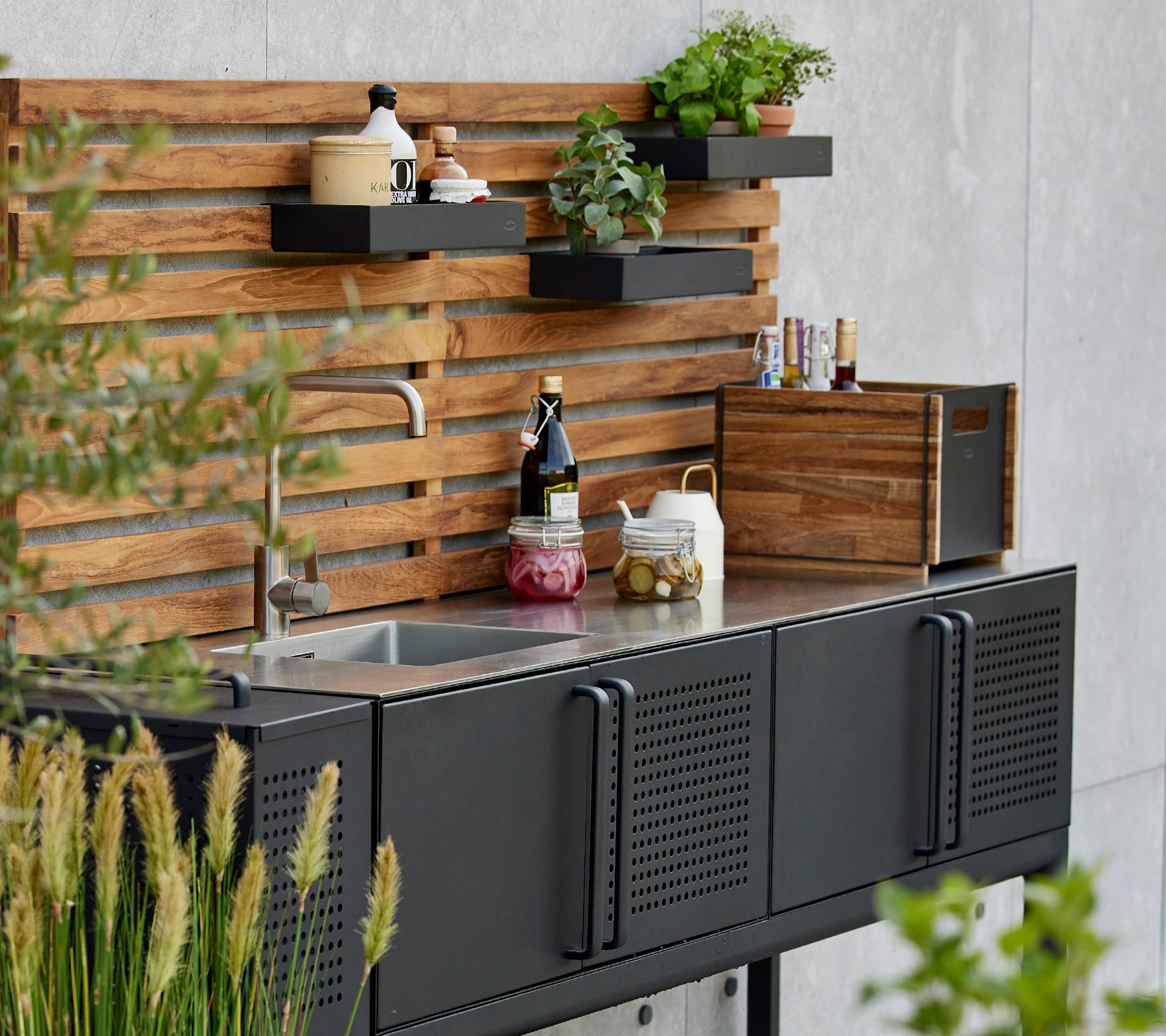 Schlichte Aufbewahrungsbox auf einer funktionalen Küchenarbeitsplatte mit Pflanzen und Gewürzen, die vor einem stilvollen Holz-Hintergrund präsentiert werden.