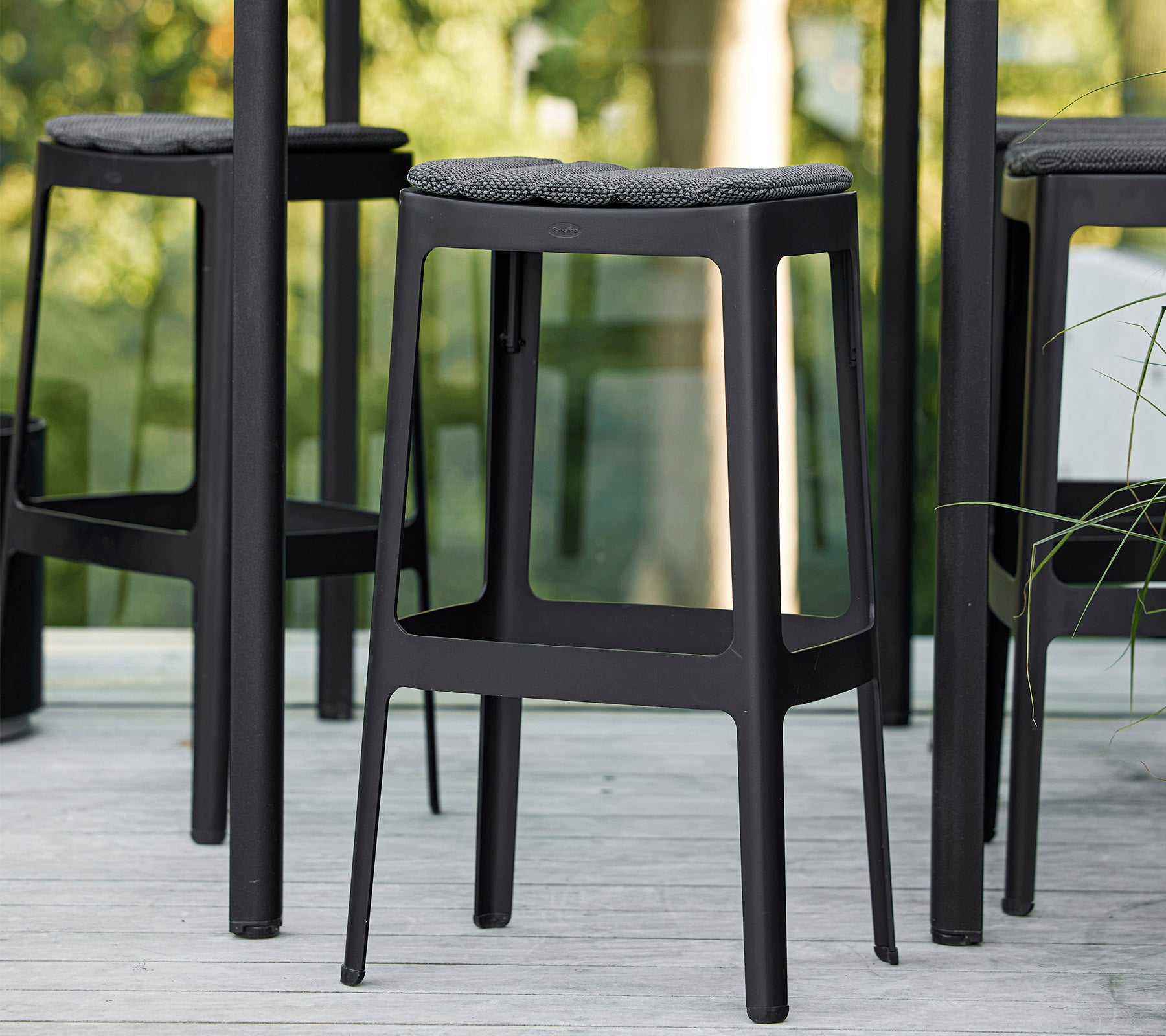 Schwarze Barhocker mit minimalistischer Design und gepolsterten Sitzen, eng beieinander angeordnet, die eine moderne Ästhetik präsentieren.