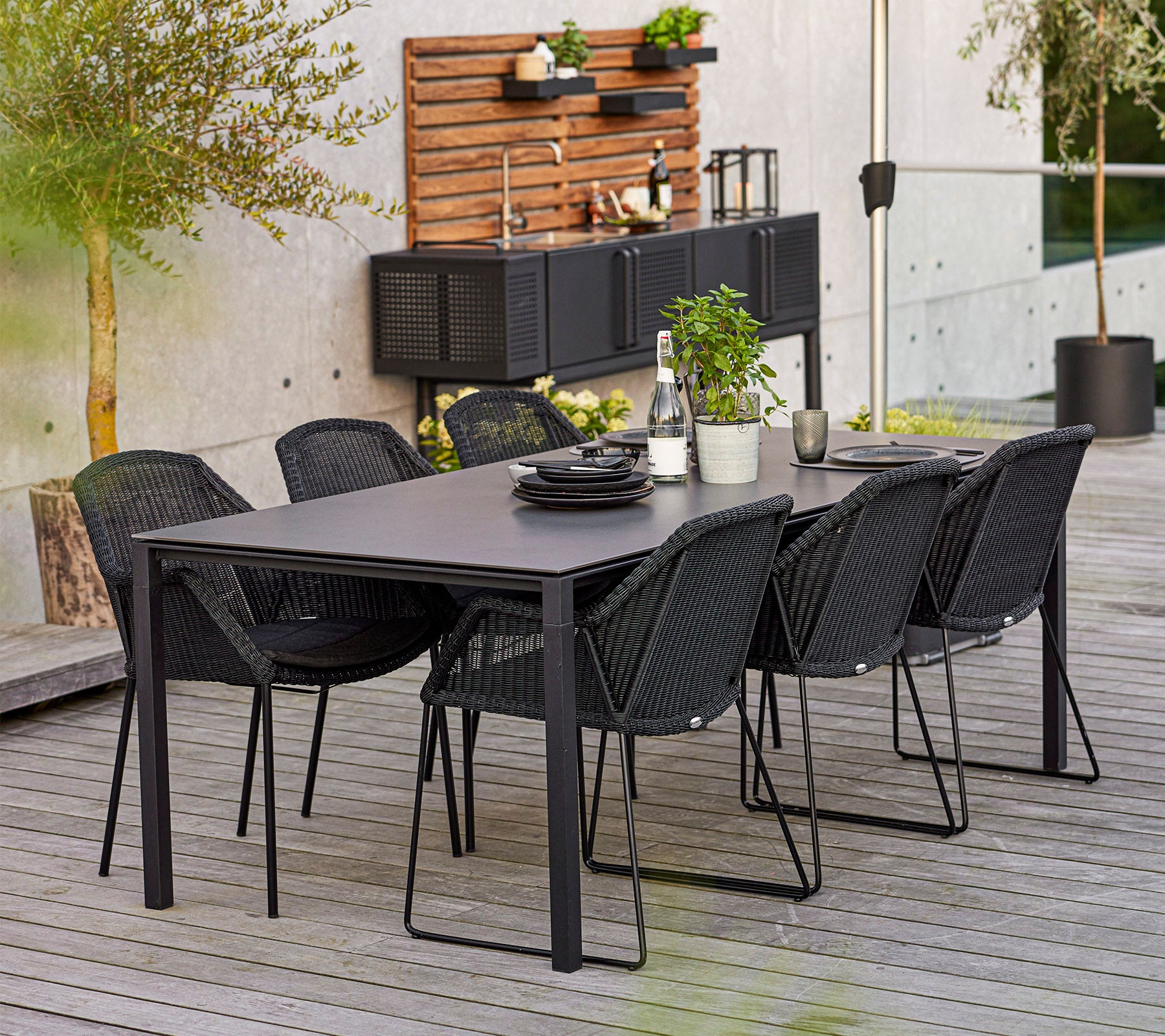 Ein modernes Esszimmer-Set mit einem rechteckigen Tisch und sechs stylischen Stühlen, ergänzt durch dekorative Pflanzen und Geschirr.