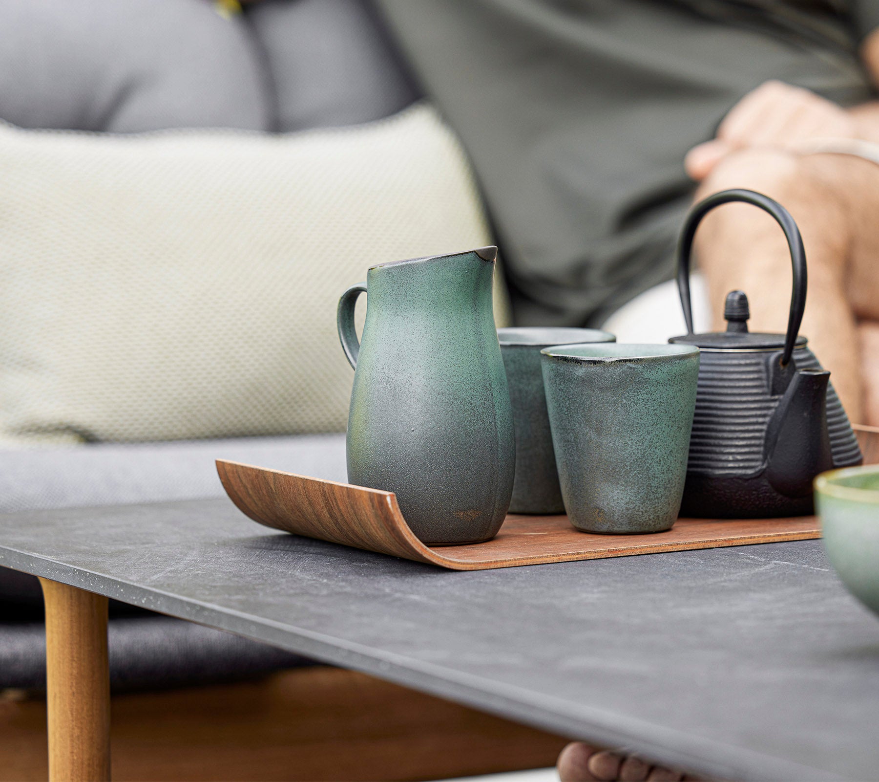 Eine stilvolle Anordnung aus Keramikkanne, Tassen und einer Kanne auf einem Holztablett, die modernes Design und erdige Töne zeigt.