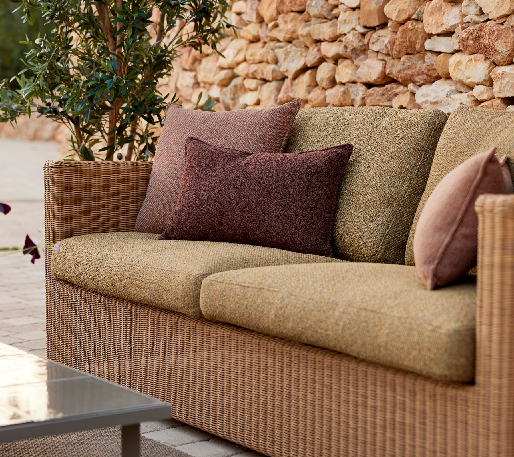Moderne beige Sofa mit lila und braunen Kissen in einer Lounge-Einstellung.