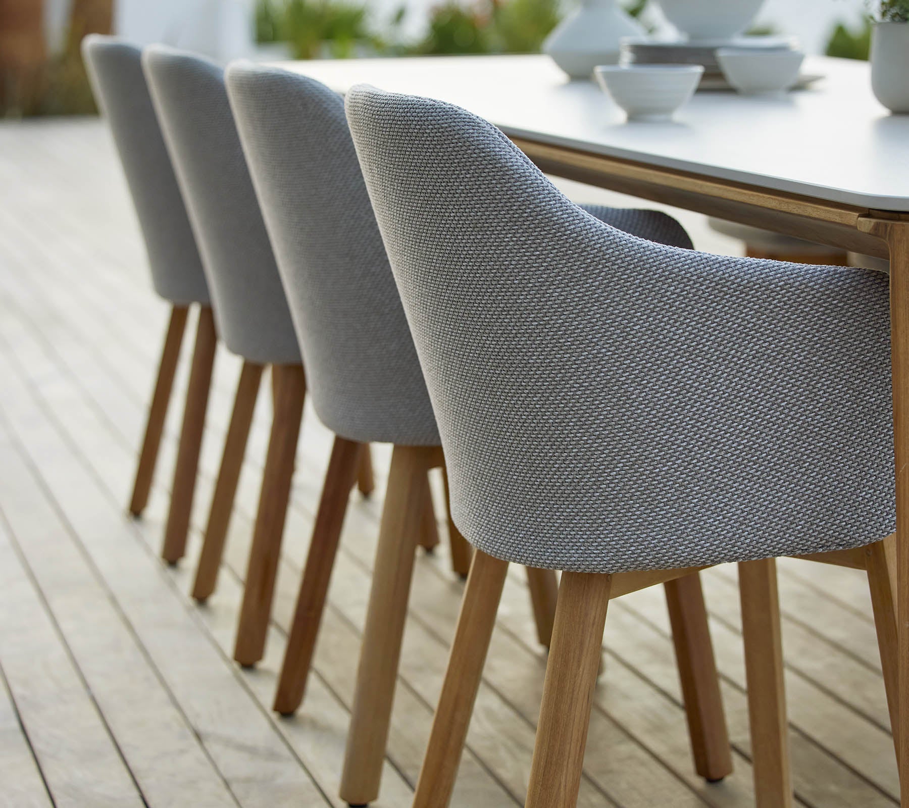 Eine Reihe moderner gepolsterter Stühle mit Holzbeinen, ordentlich neben einem Tisch angeordnet, die ein stilvolles und zeitgemäßes Design zeigen.