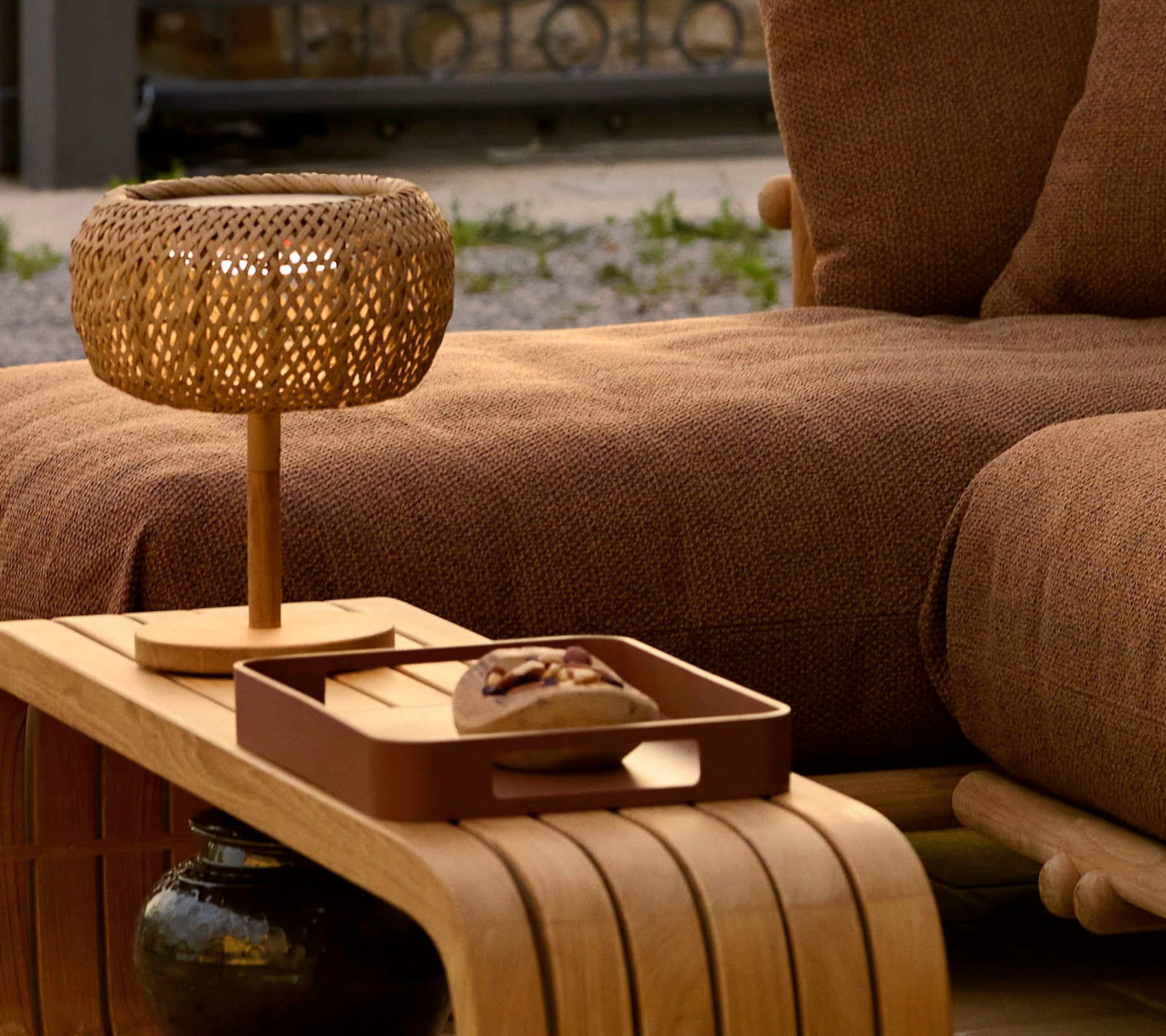 Ein Holztisch mit einer dekorativen Platte und einer geflochtenen Lampe, die eine gemütliche und stilvolle Atmosphäre unterstreicht.