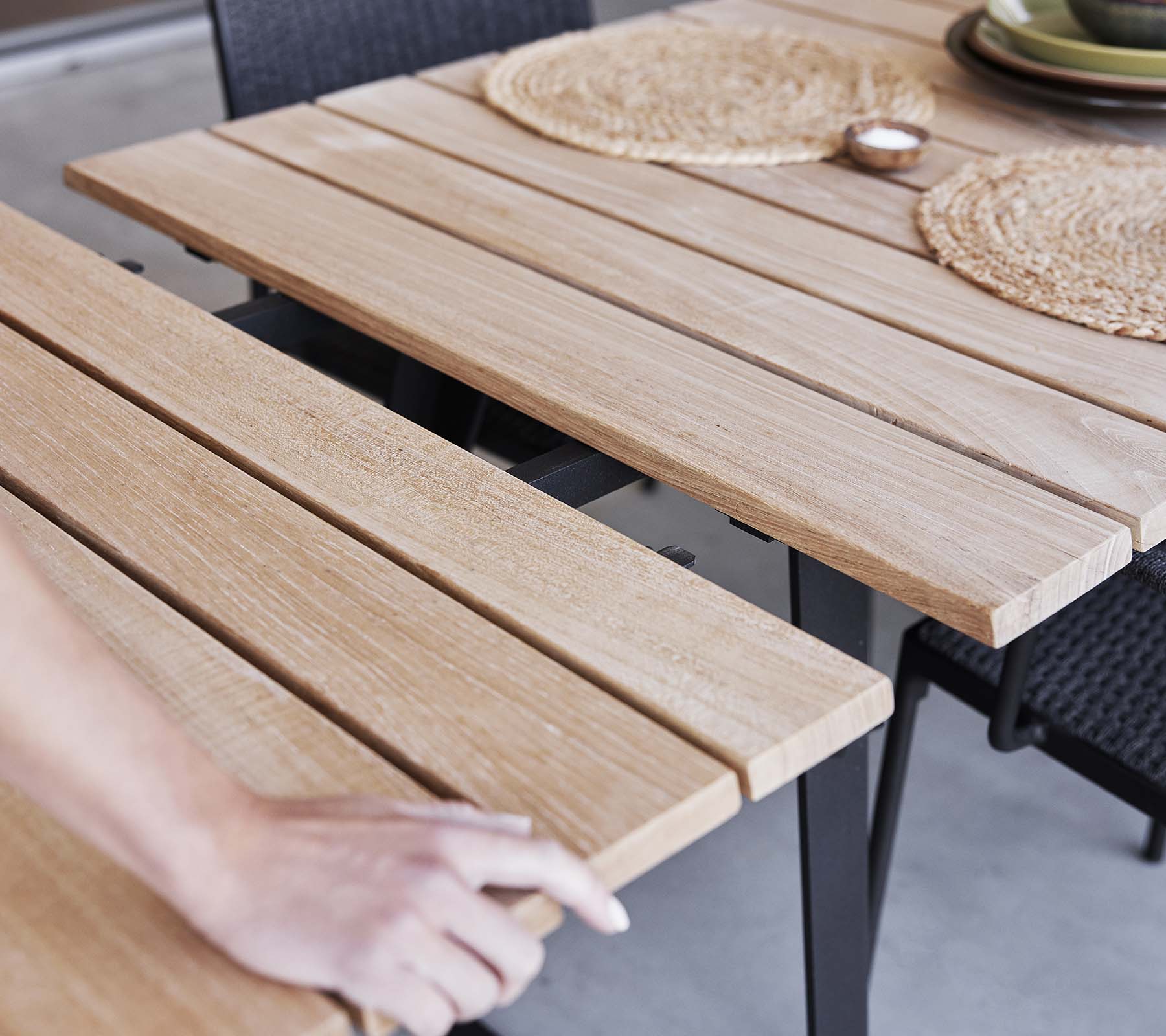 Detail eines Holztisches mit Lamellen-Design, Platzdeckchen und einer minimalistischen Ästhetik, perfekt zum Essen oder für Zusammenkünfte.