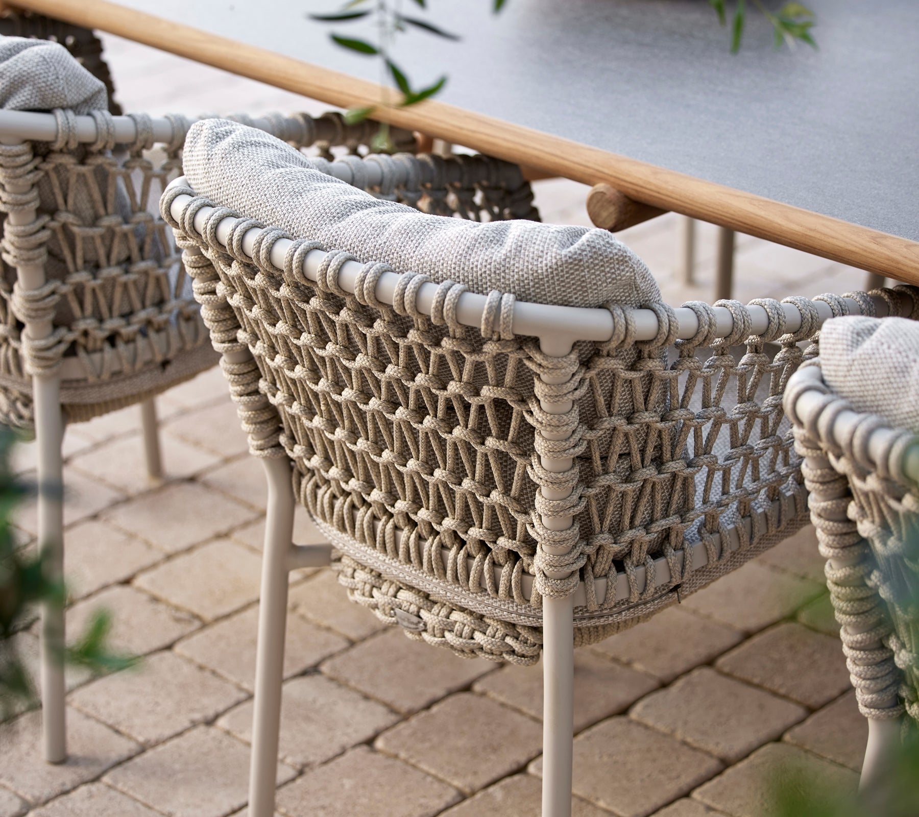 Gemütliche Essstühle mit einem geflochtenen Design und weichen Kissen, perfekt für stilvolles Essen im Freien.