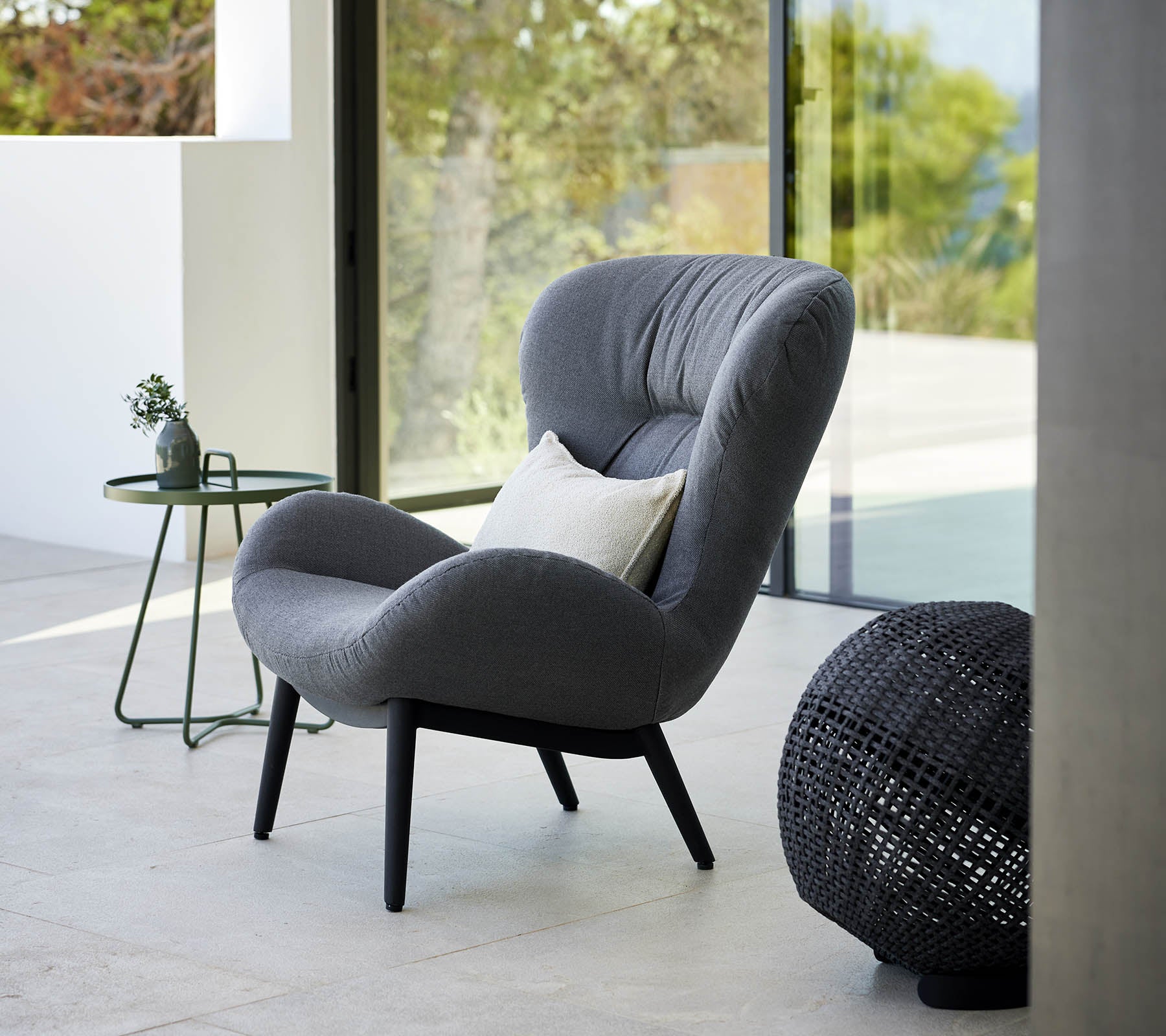 ein ruhiger Lounge-Stuhl mit modernem Design, der über eine plüschige Polsterung und elegante Beine verfügt, begleitet von einem kleinen Beistelltisch und dekorativen Akzenten.
