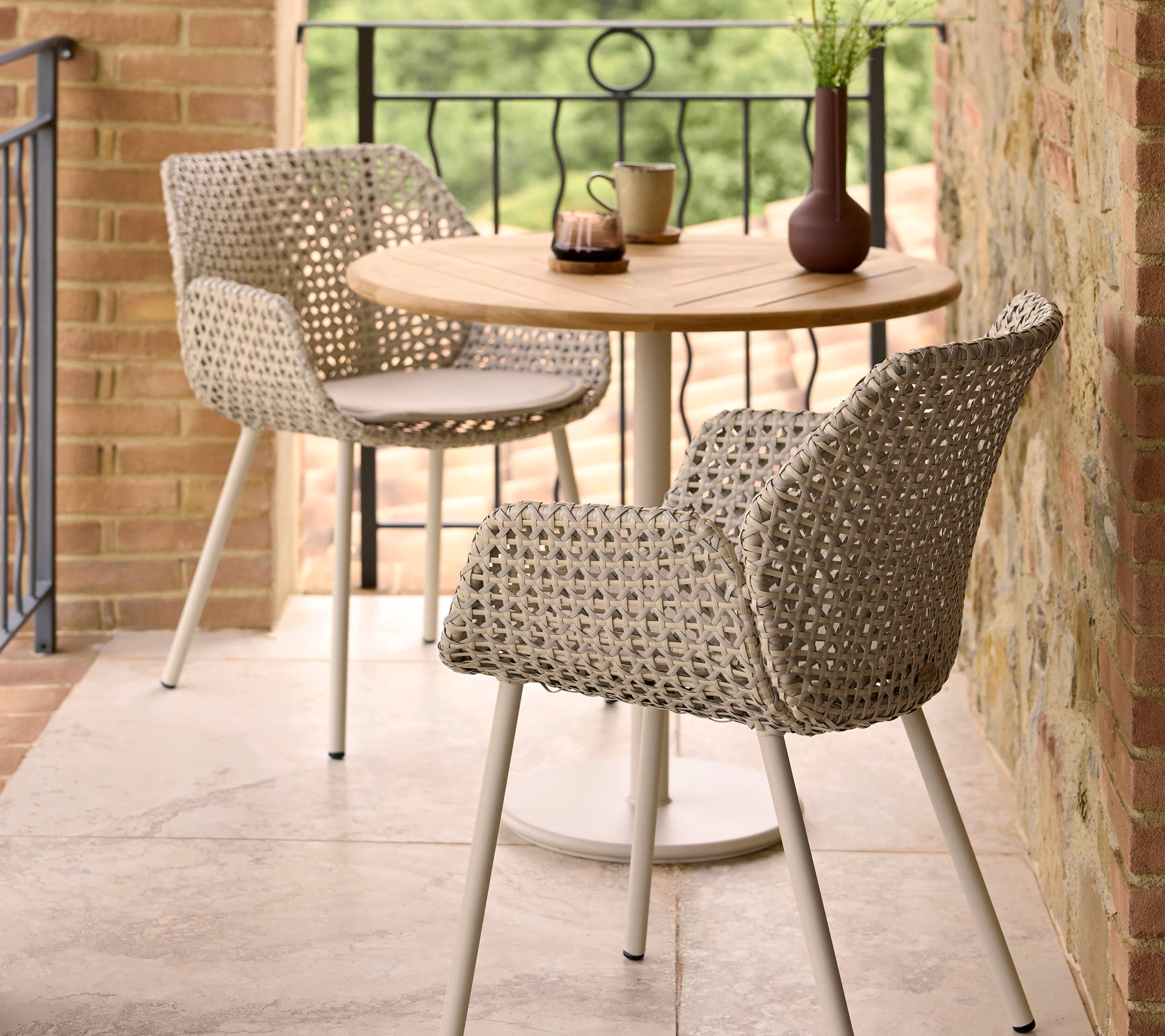 Stylische Vibe Essstühle kombiniert mit einem runden Go Café-Tisch, ergänzt durch dekorative Gegenstände auf dem Tisch.