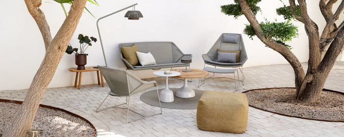 Moderne Lounge-Einstellung mit einem grauen Sofa, einem grauen Stuhl, einem Holztisch und einem gelben Pouf.