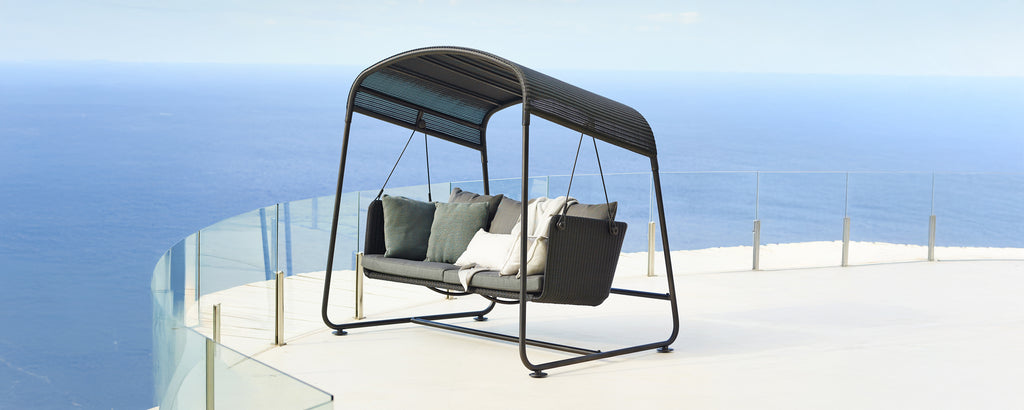 Moderne Sch swing sitz mit grauen Kissen und schwarzem Rahmen mit Blick auf eine malerische Aussicht.