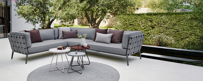 Modernes graues Ecksofa mit lila Kissen und einem runden Couchtisch in einem Lounge-Bereich.