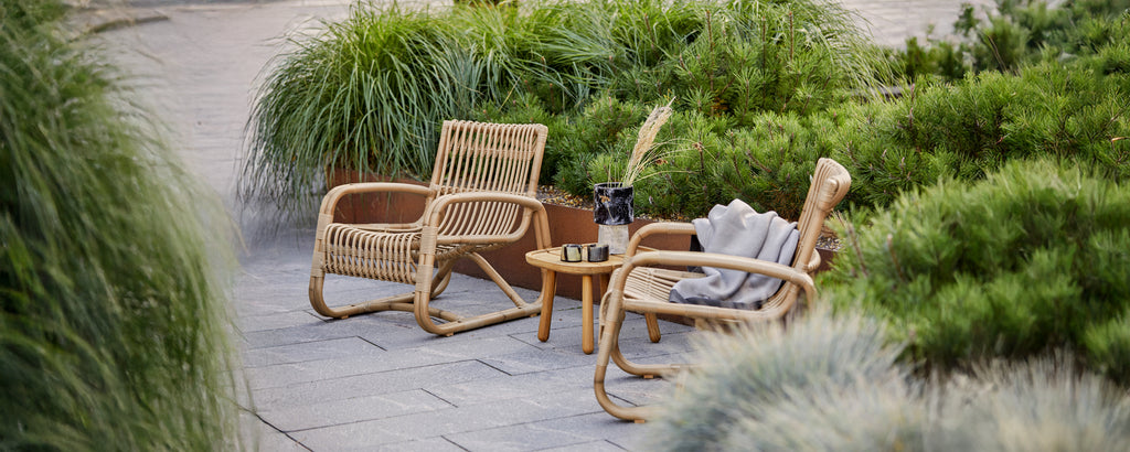 Böhmischer Lounge-Bereich mit Rattanstühlen und einem kleinen Tisch mit einem grauen Kissen.