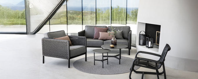 Moderner Loungebereich mit einem grauen Sofa, einem schwarzen Sessel und einem runden Couchtisch.