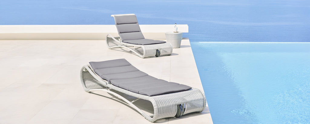 Moderne graue und weiße Loungesessel neben einem Schwimmbecken.