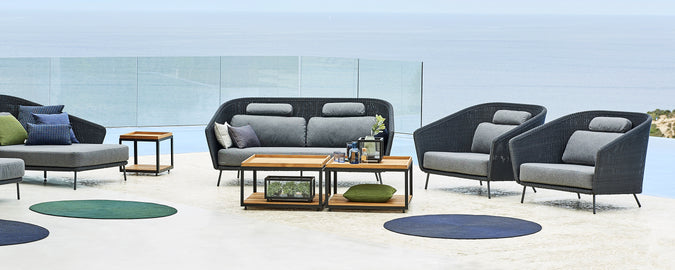 Moderne Lounge-Bereich mit grauem Sofa, schwarzen Armlehnsesseln und Holztisch.