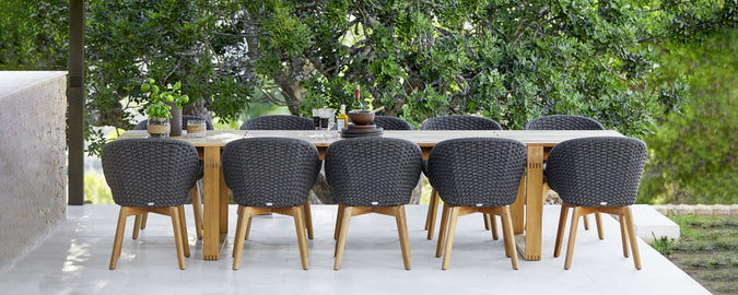 Modernes Gartenessensemble mit schwarzen Stühlen und einem Holztisch.