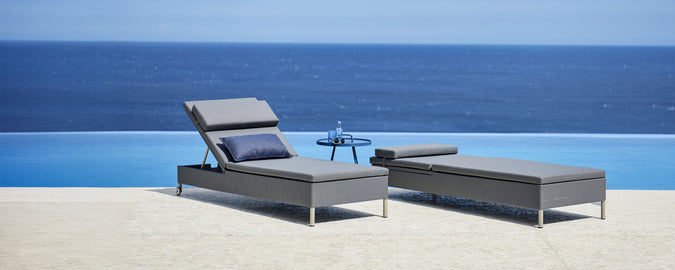 Grauer Lounge-Stuhl und Chaiselongue neben einem Pool mit Blick auf den Ozean.