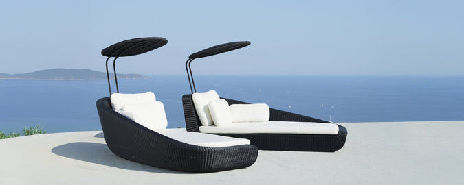 Moderne schwarze Loungestühle mit weißen Kissen mit Blick auf das Meer.