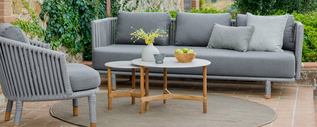 Moderne Außenlounge-Bereich mit einem grauen Sofa, einem grauen Stuhl und einem Holztisch.