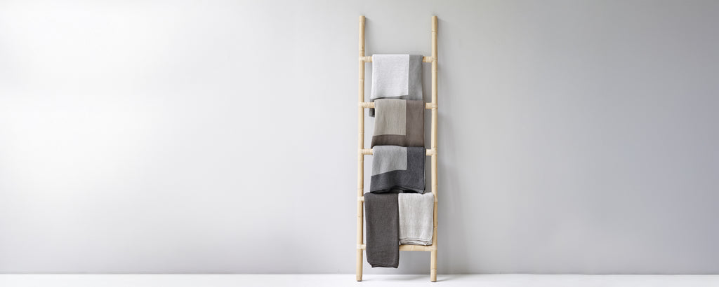 Moderne Handtuchleiter, die beige, graue und weiße Handtücher präsentiert.