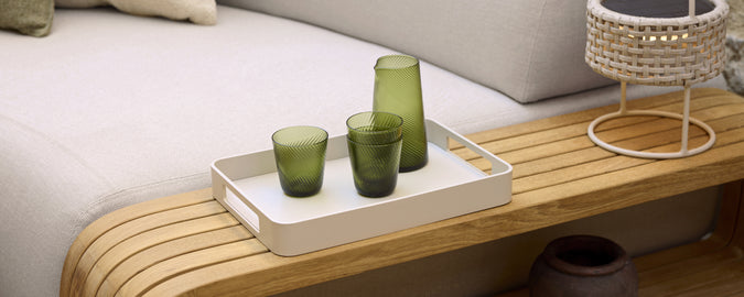 Moderne Lounge-Setting mit grünem Glas auf einem weißen Tablett.