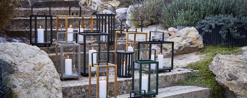 Moderne Außenlaternen in Schwarz, Gold und Grün auf Steintreppen angeordnet.