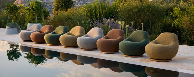 A row of modern chairs in beige, grey, brown, green, and terracotta beside a pool.