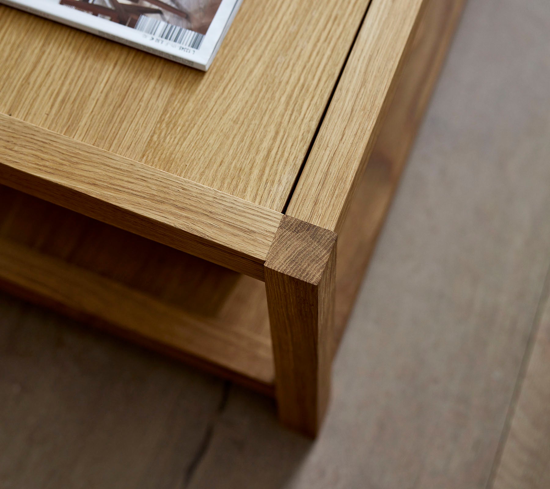 Holzkaffee-Tisch mit einem klaren Design, der ein darauf liegendes Magazin und ein minimalistisches Unterregal für zusätzlichen Stauraum bietet.