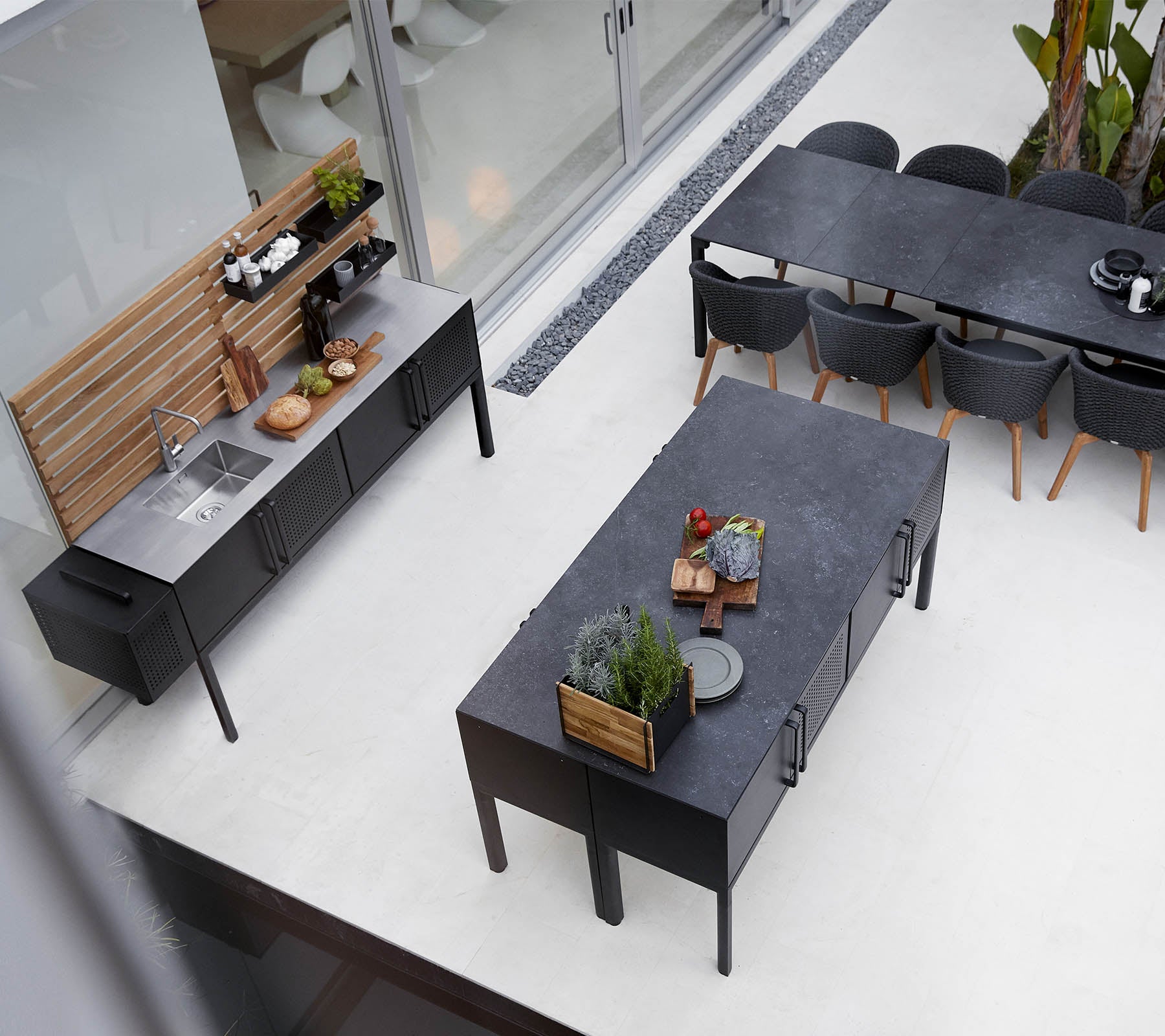 Moderne Außengrillküche mit einer eleganten Arbeitsplatte, einem geräumigen Esstisch und stilvollen Sitzgelegenheiten mit Pflanzen und Dekorationselementen.