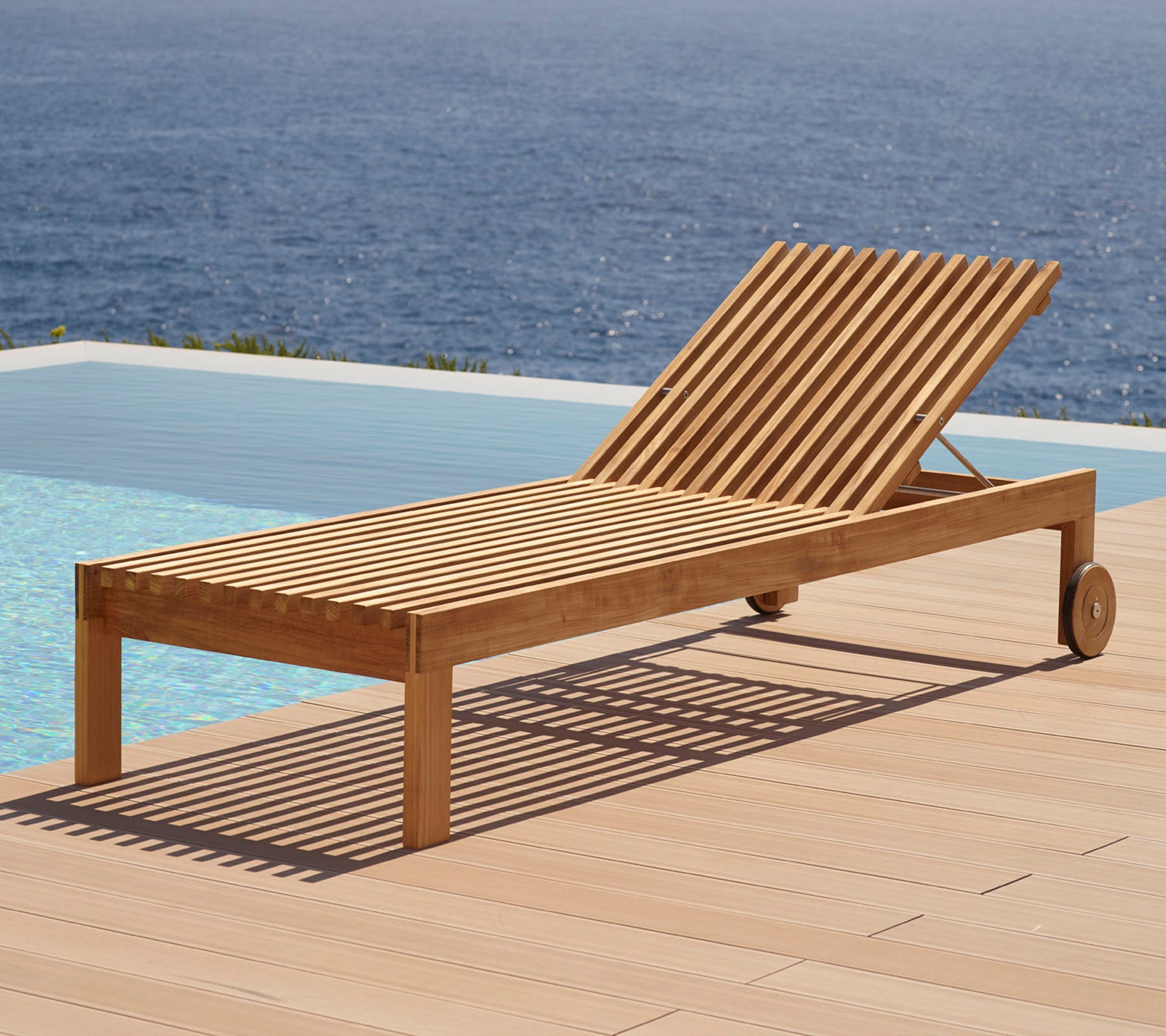 Holz-Lounge-Stuhl mit Lamellen-Design, ausgestattet mit Rädern und neben einem Swimmingpool mit Wasserblick im Hintergrund positioniert.