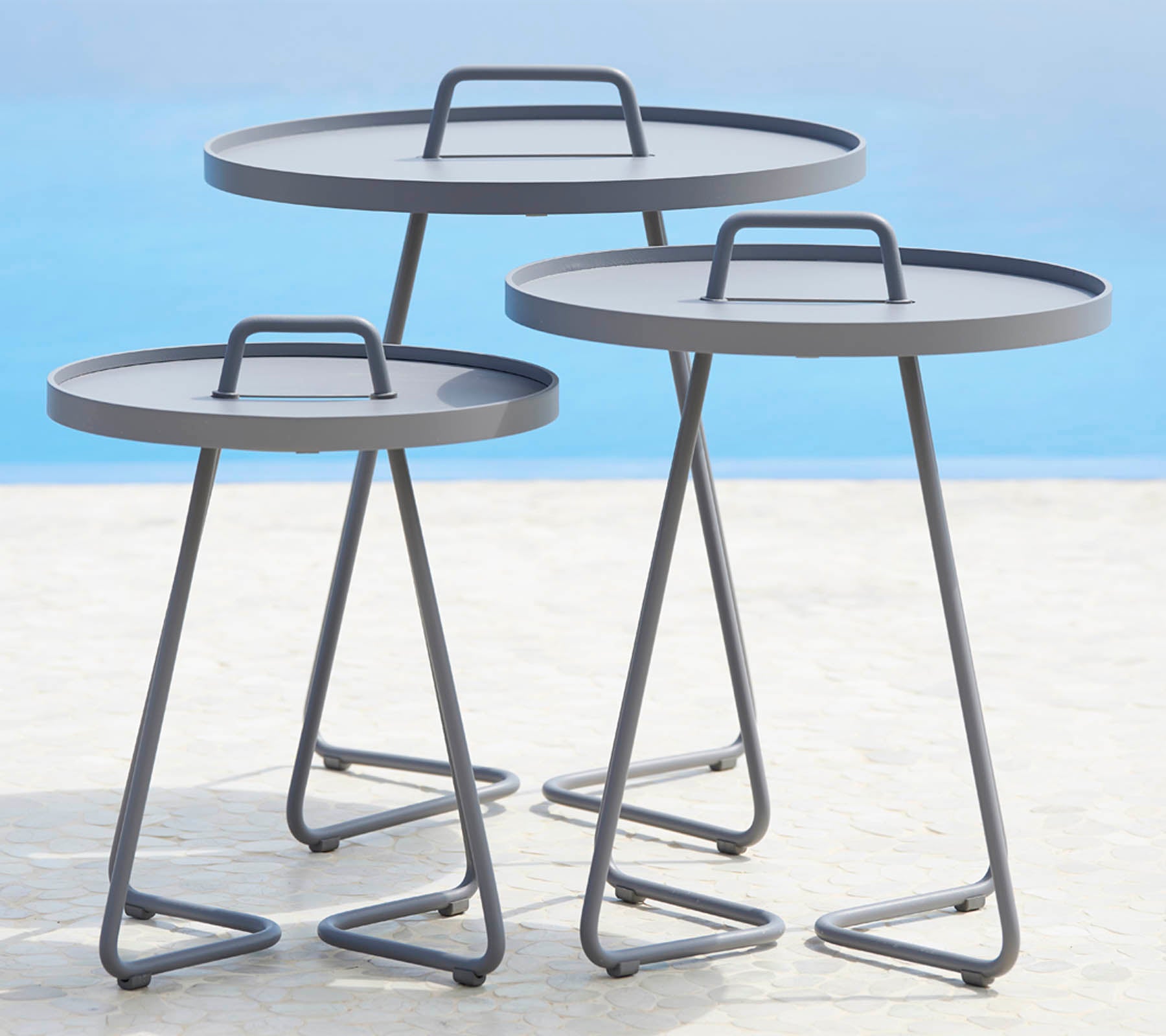 Drei moderne runde Tische mit schlanken Metallrahmen und flachen Oberflächen, angeordnet in unterschiedlichen Größen. Perfekt für vielseitige Styling-Optionen.