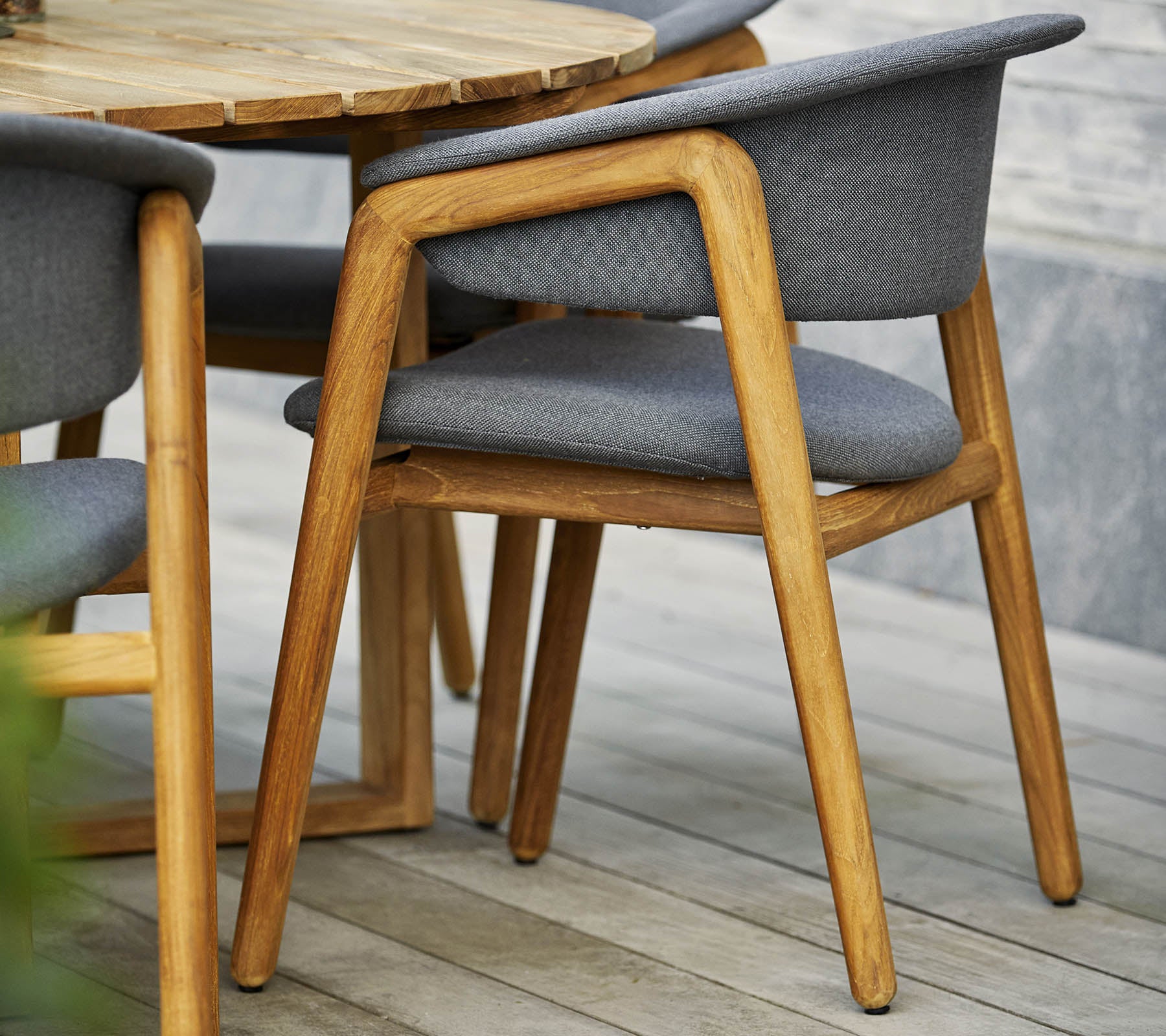 Stilvoller Holzstuhl mit grauem gepolstertem Sitz und Rückenlehne, kombiniert mit einem runden Tisch im zeitgenössischen Design.