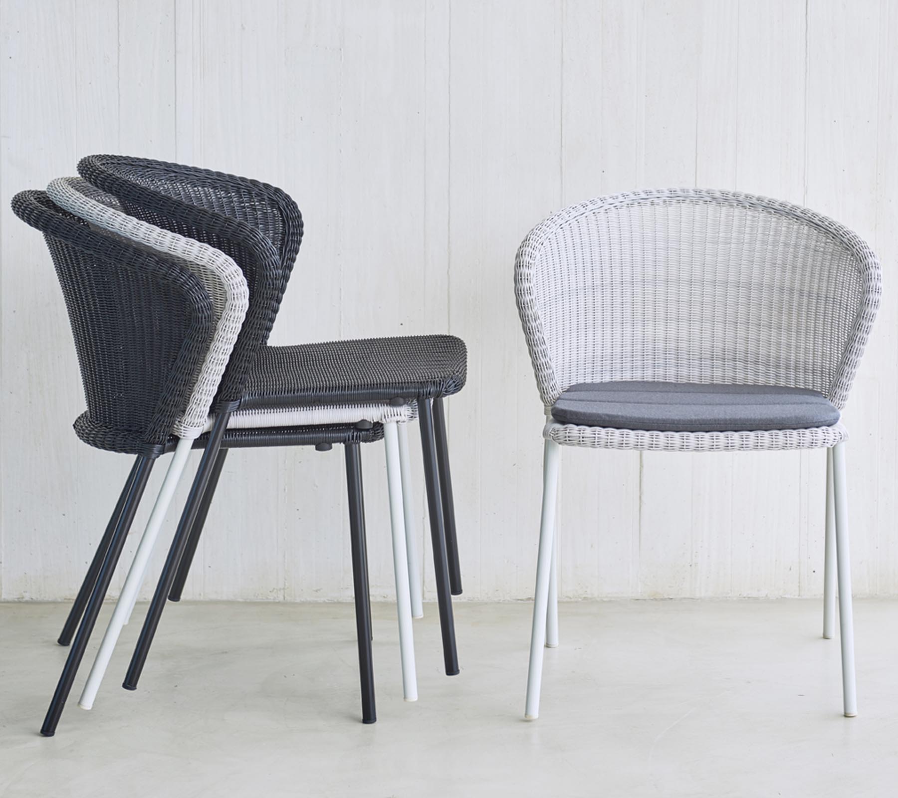 Stapel moderner, gewebter Stühle in Schwarz und Weiß mit gepolsterter Sitzfläche, ideal für stilvolle Sitzlösungen.