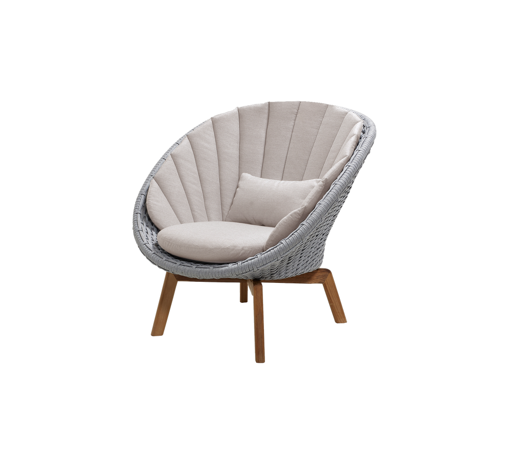 Moderner hellgrauer Stuhl mit sandfarbenem Kissen in einem Loungebereich.