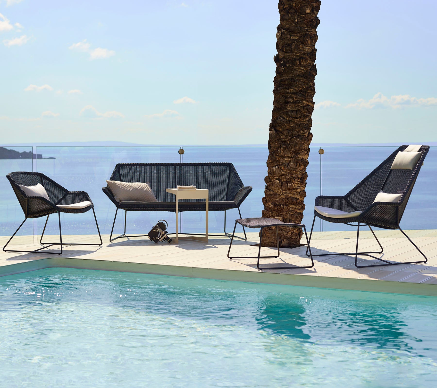 Moderne Loungesessel mit schwarzen Stühlen und einem Loveseat neben einem Pool.