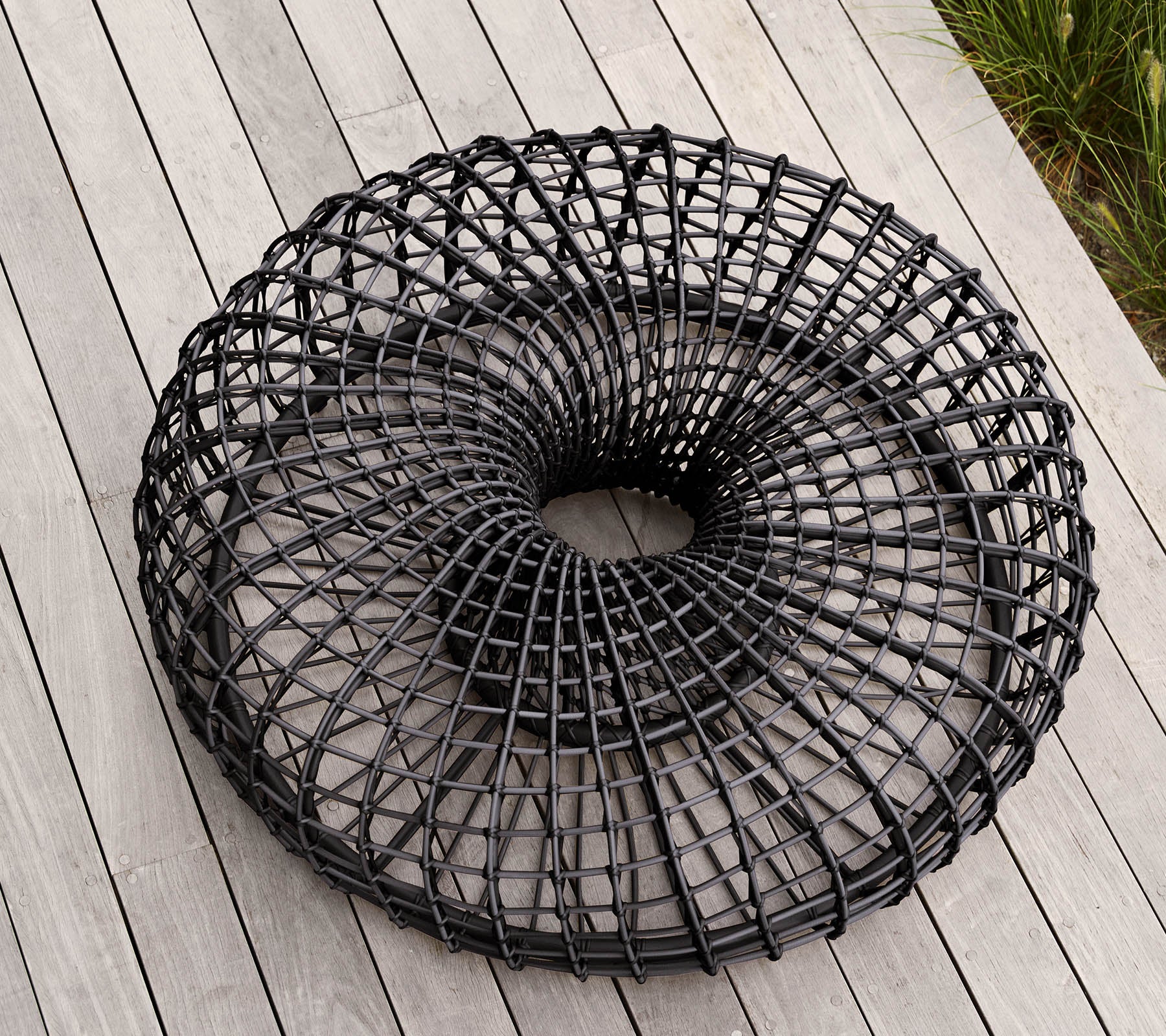 Moderne, runde schwarze Drahtkorb mit einem einzigartigen offenen Geflechtsdesign, das auf einer flachen Oberfläche ruht. Ideal für Lagerung oder dekorative Zwecke.