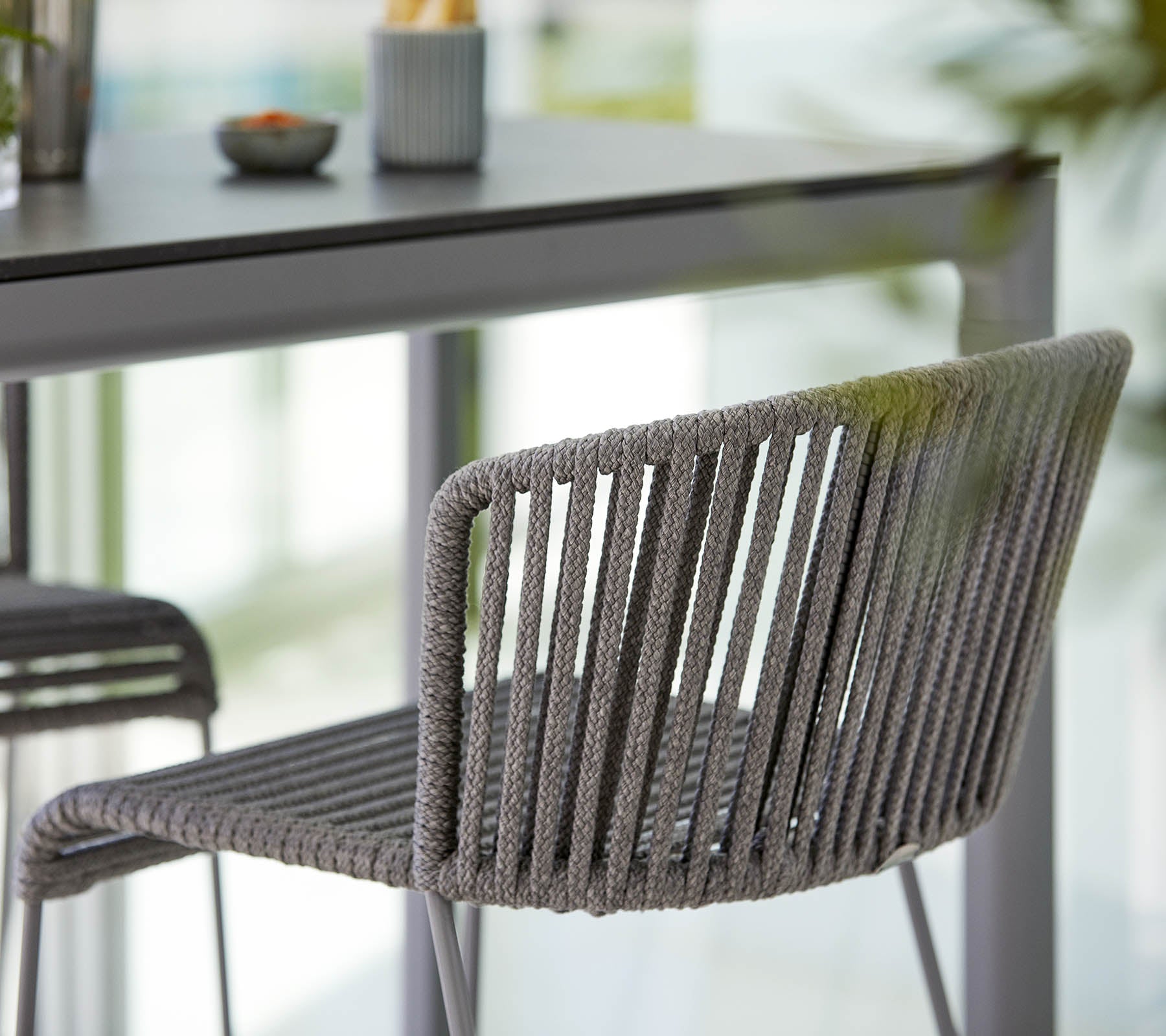 Stylischer grauer Stuhl mit einem schlanken Design, das vertikale Streifen und eine moderne Ästhetik aufweist, neben einem minimalistischen Tisch platziert.