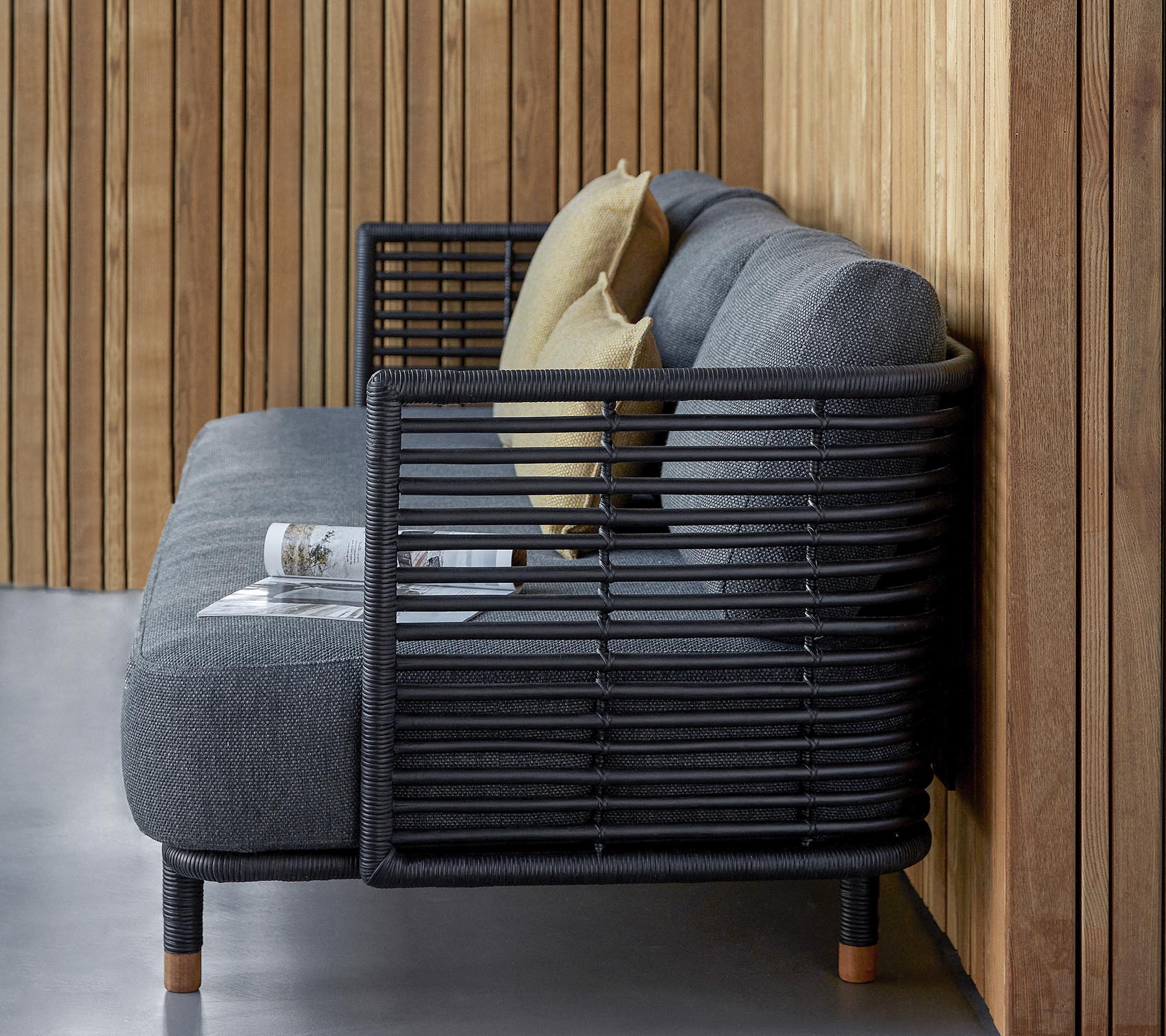 Stilvolles Sofa mit einem schlanken Design aus strukturiertem grauen Stoff und dekorativen Kissen, ergänzt durch ein modernes Lattenrahmen.
