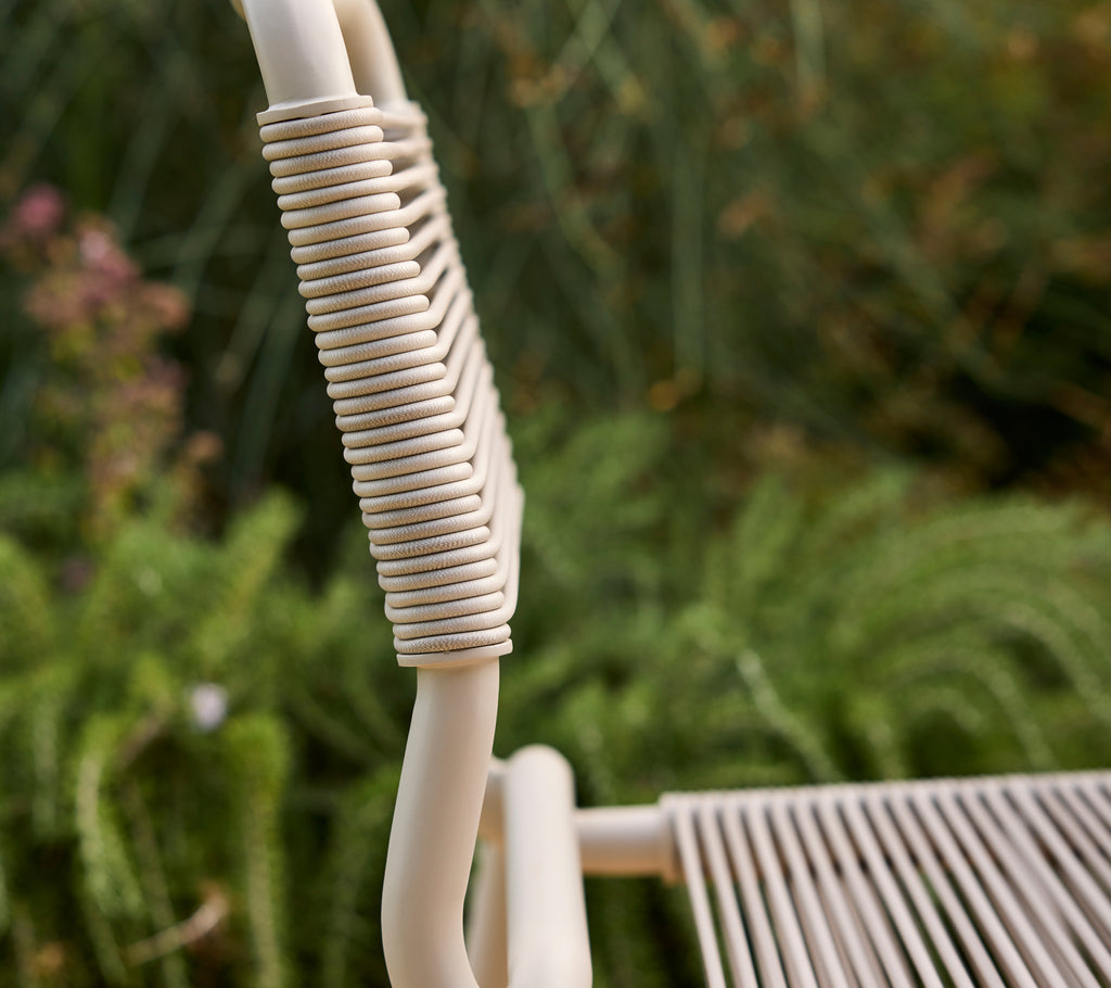 Beige Stuhl teilweise sichtbar mit einem verschwommenen grünen Hintergrund.