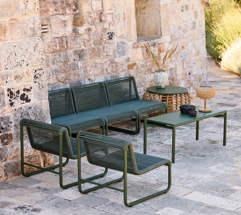 Moderne grüne Couch und Stühle mit einem passenden Tisch in einer lässigen Lounge-Umgebung.