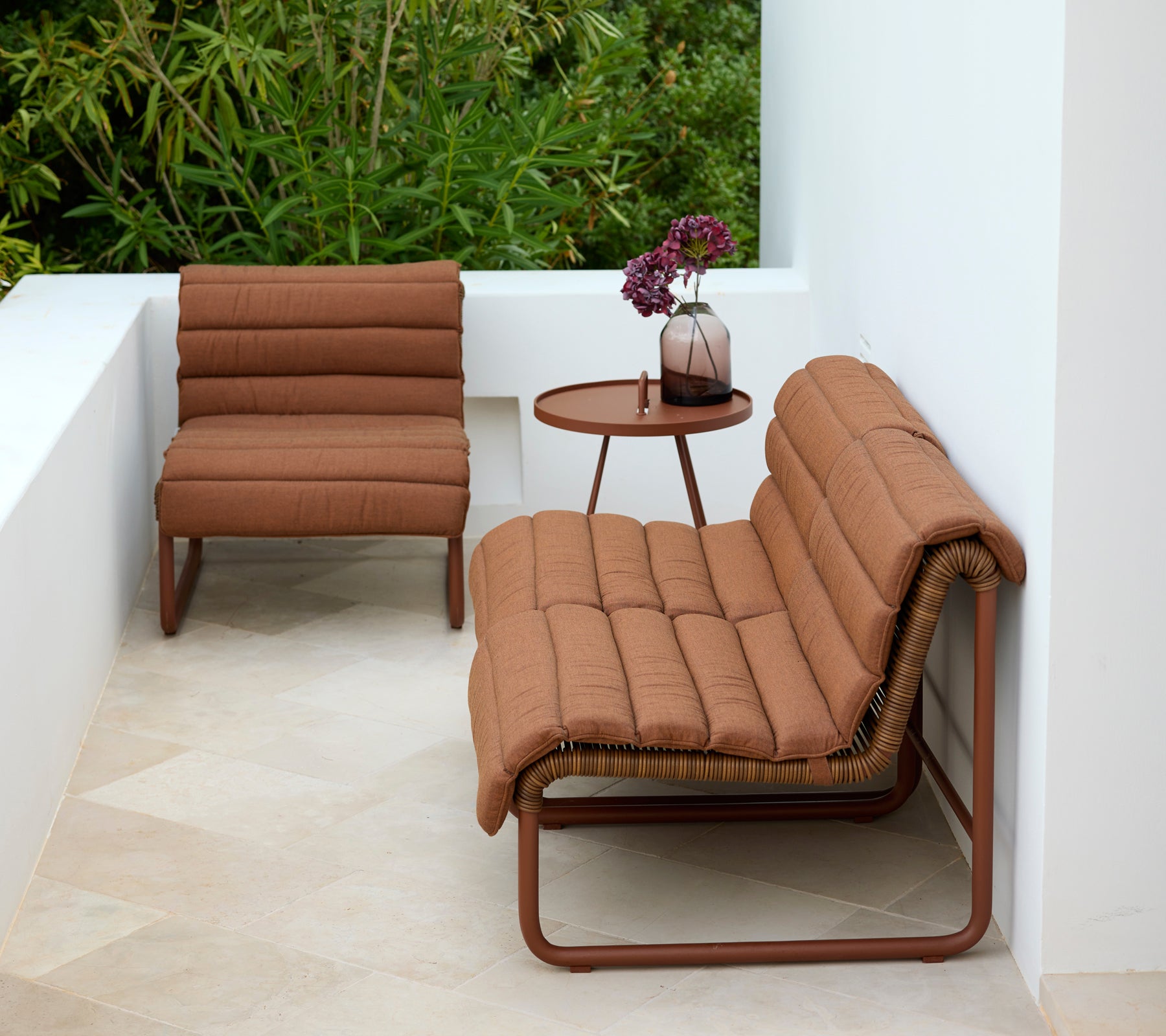 Brauner Lounge-Stuhl und Loveseat mit einem runden Beistelltisch in einer modernen Outdoor-Umgebung.