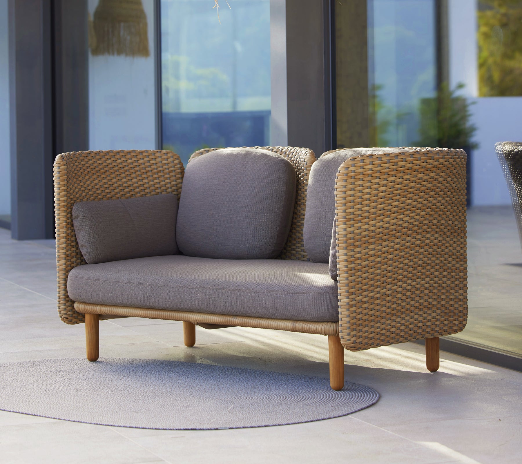 Arch 2-Sitzer-Sofa mit niedriger Rückenlehne, gewebten Seiten und neutralen Kissen, das Komfort mit modernem Design vereint.