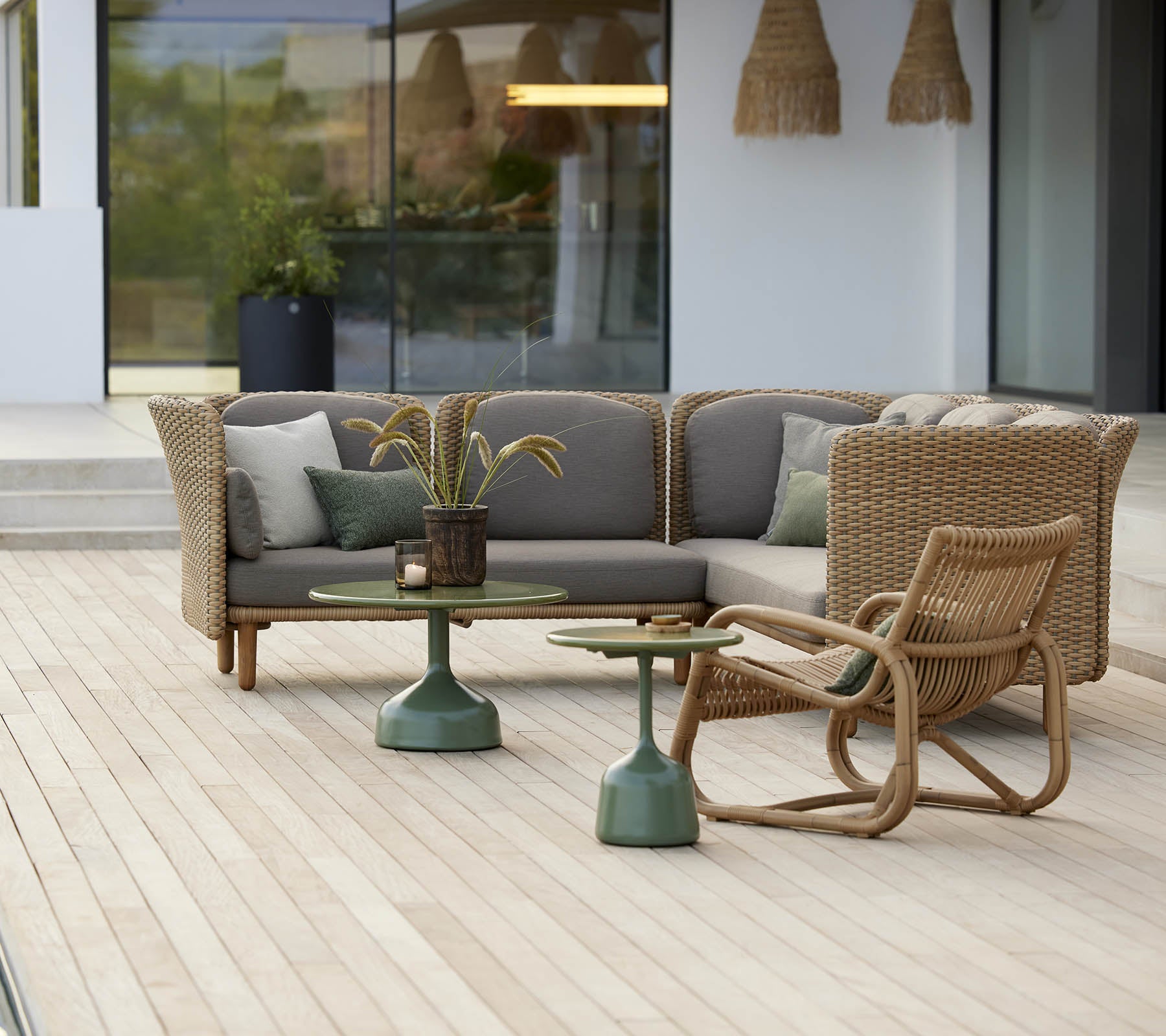 Stilvoller Sitzbereich mit einem geschwungenen Lounge-Stuhl und einem Tisch mit grünem Fuß, ergänzt durch weiche Kissen und dekorative Elemente.
